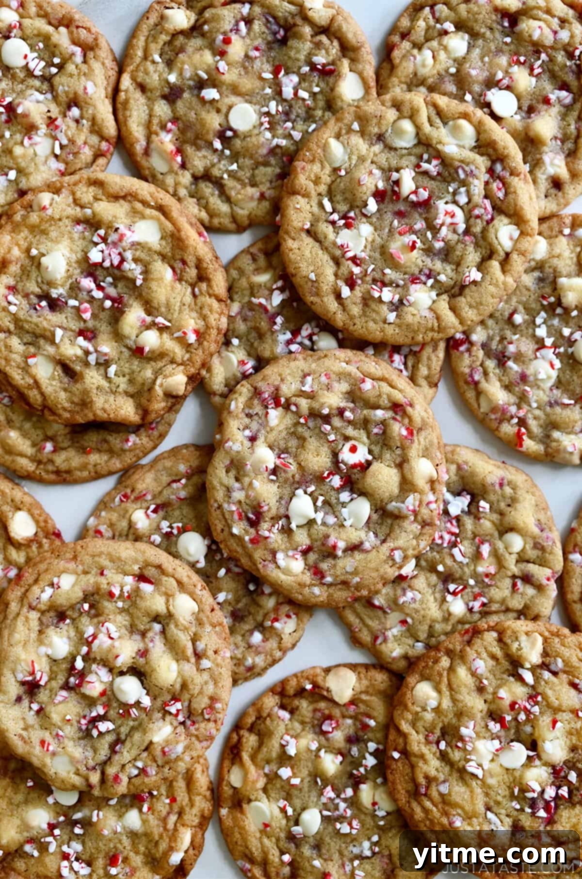 White chocolate chip cookies studded with crushed candy canes piled atop each other.