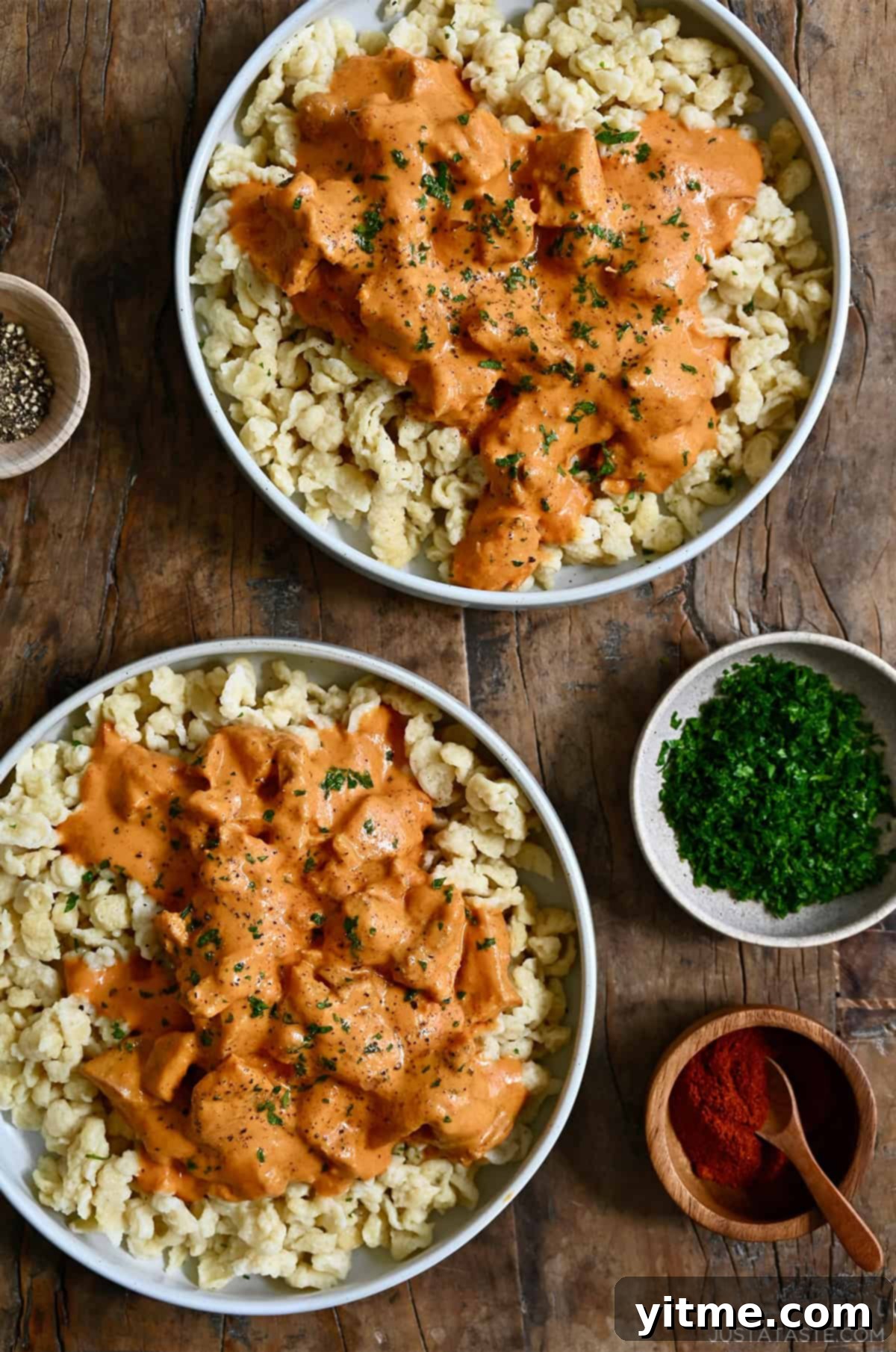 Two plates of Hungarian Chicken Paprikash served over nokedli.