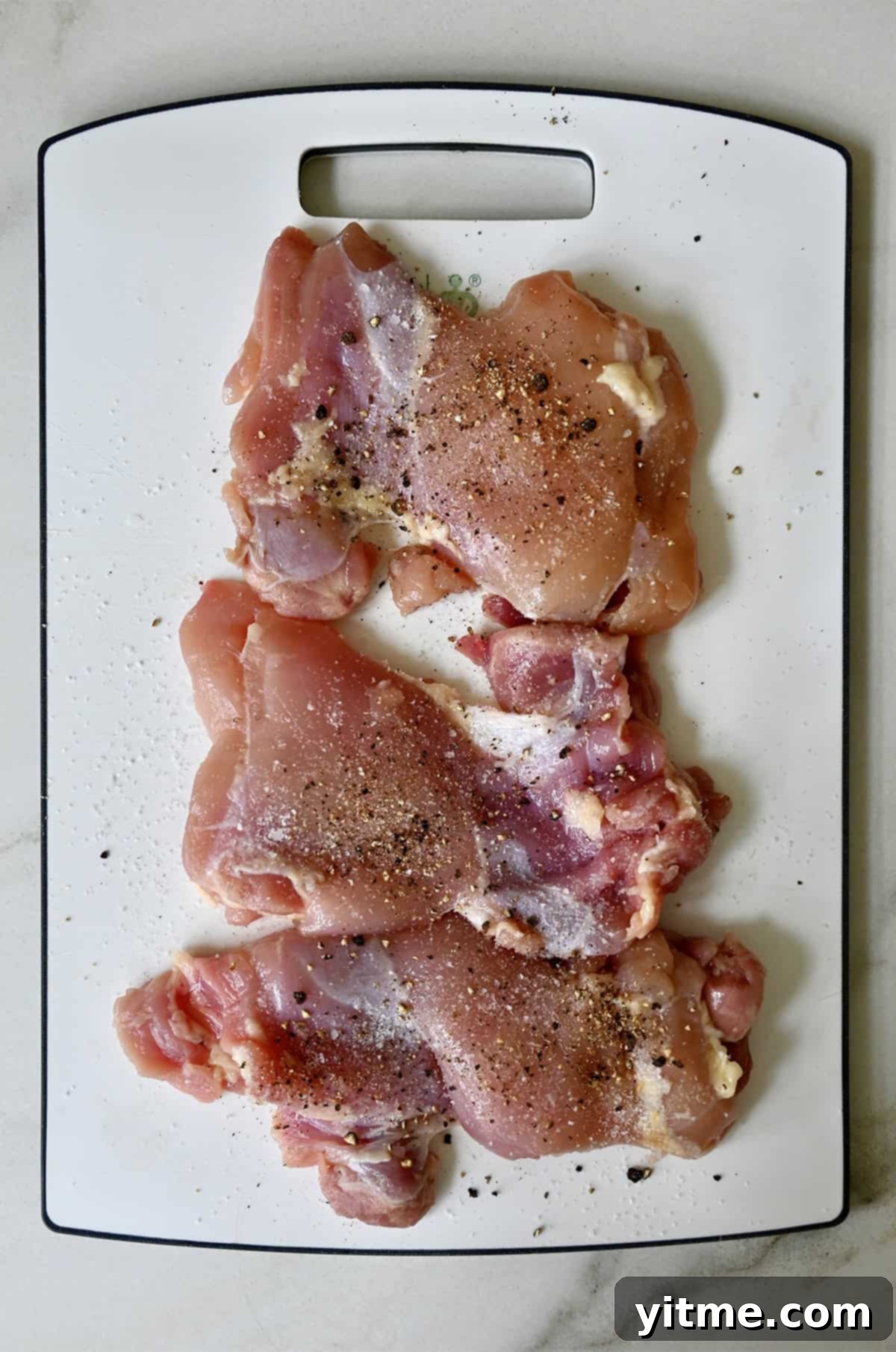 Chicken thighs seasoned with salt and pepper.