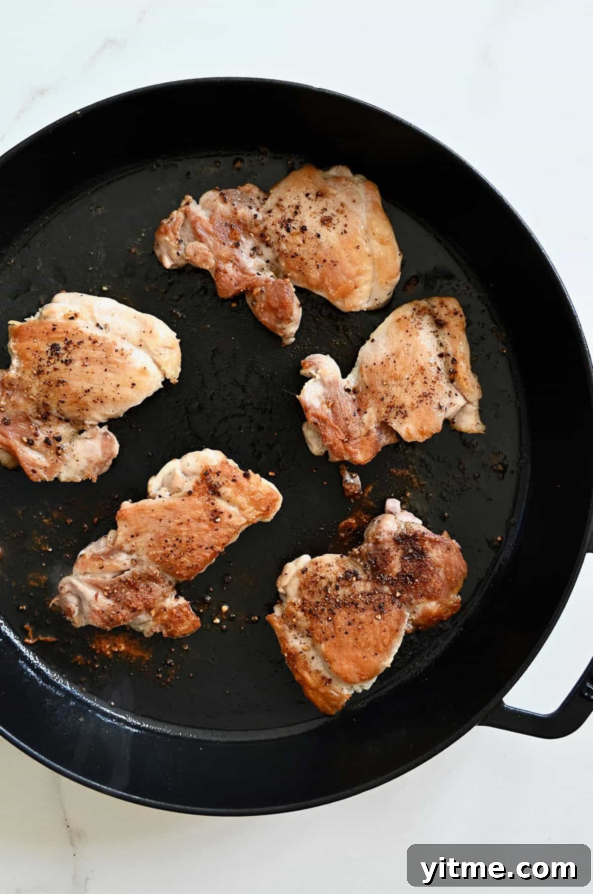 Seared chicken thighs in a pan.