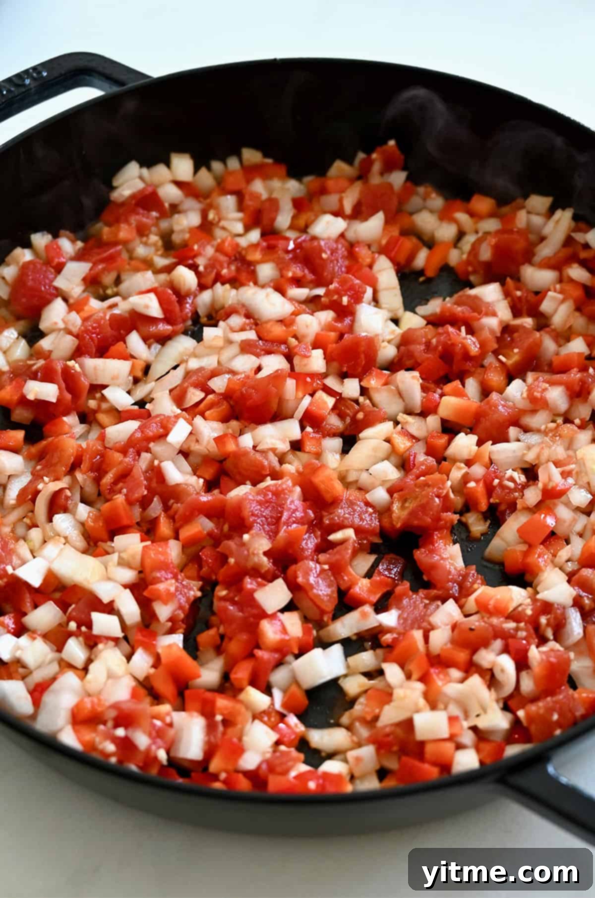 Diced veggies cooking in a skillet.