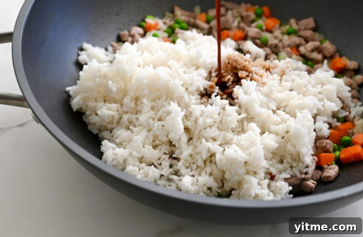 Adding soy sauce to fried rice in a skillet