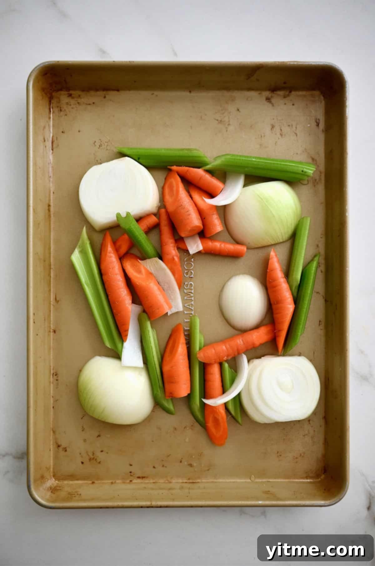 Large-chopped carrots, celery and onion on a baking sheet to create a veggie "roasting rack" for cooking turkey, adding flavor to both the turkey and drippings.