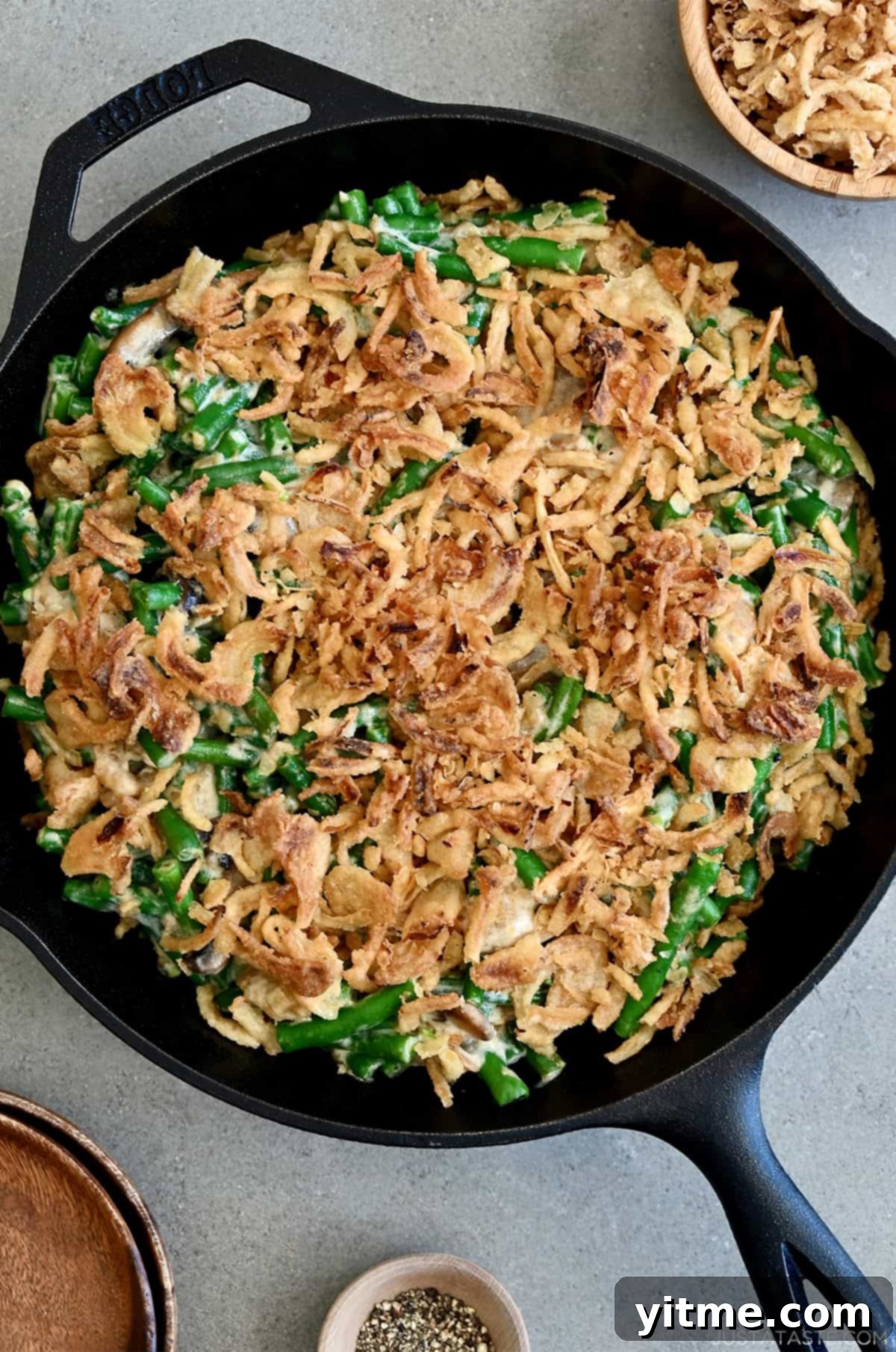Creamy green bean casserole topped with French's crispy fried onions in a cast iron skillet, ready to serve.