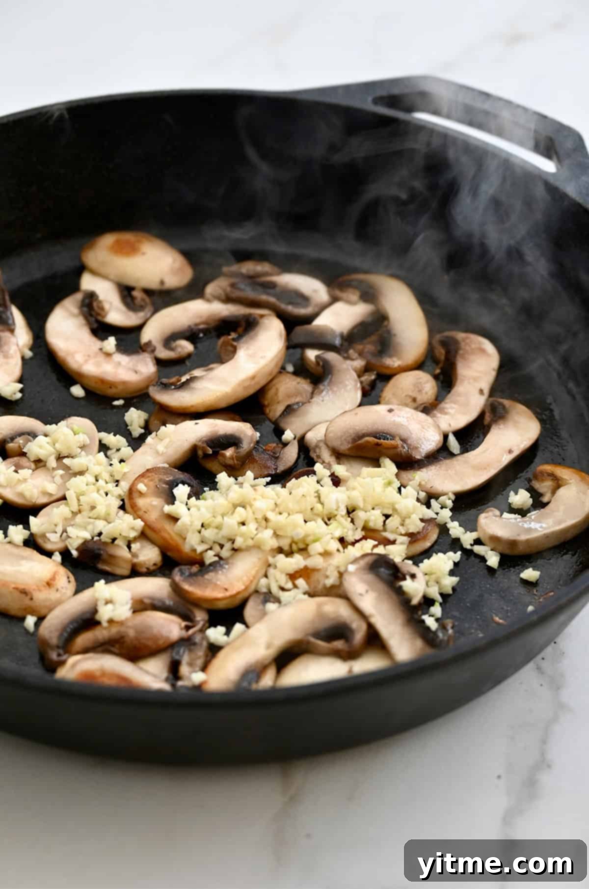 Sautéed mushrooms and garlic sizzling in a cast iron skillet, building flavor.