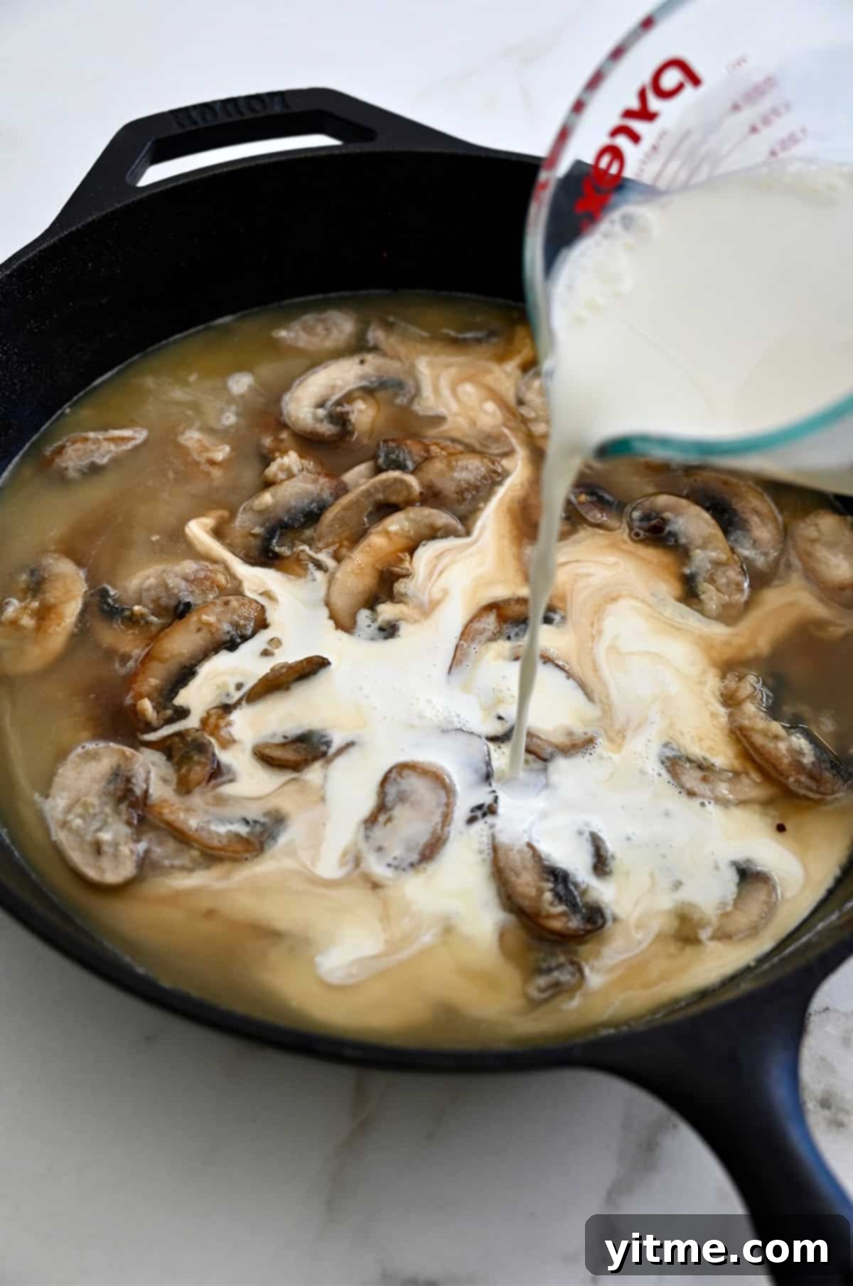 Half-and-half being added to the mushroom sauce in a skillet, creating a rich cream sauce.
