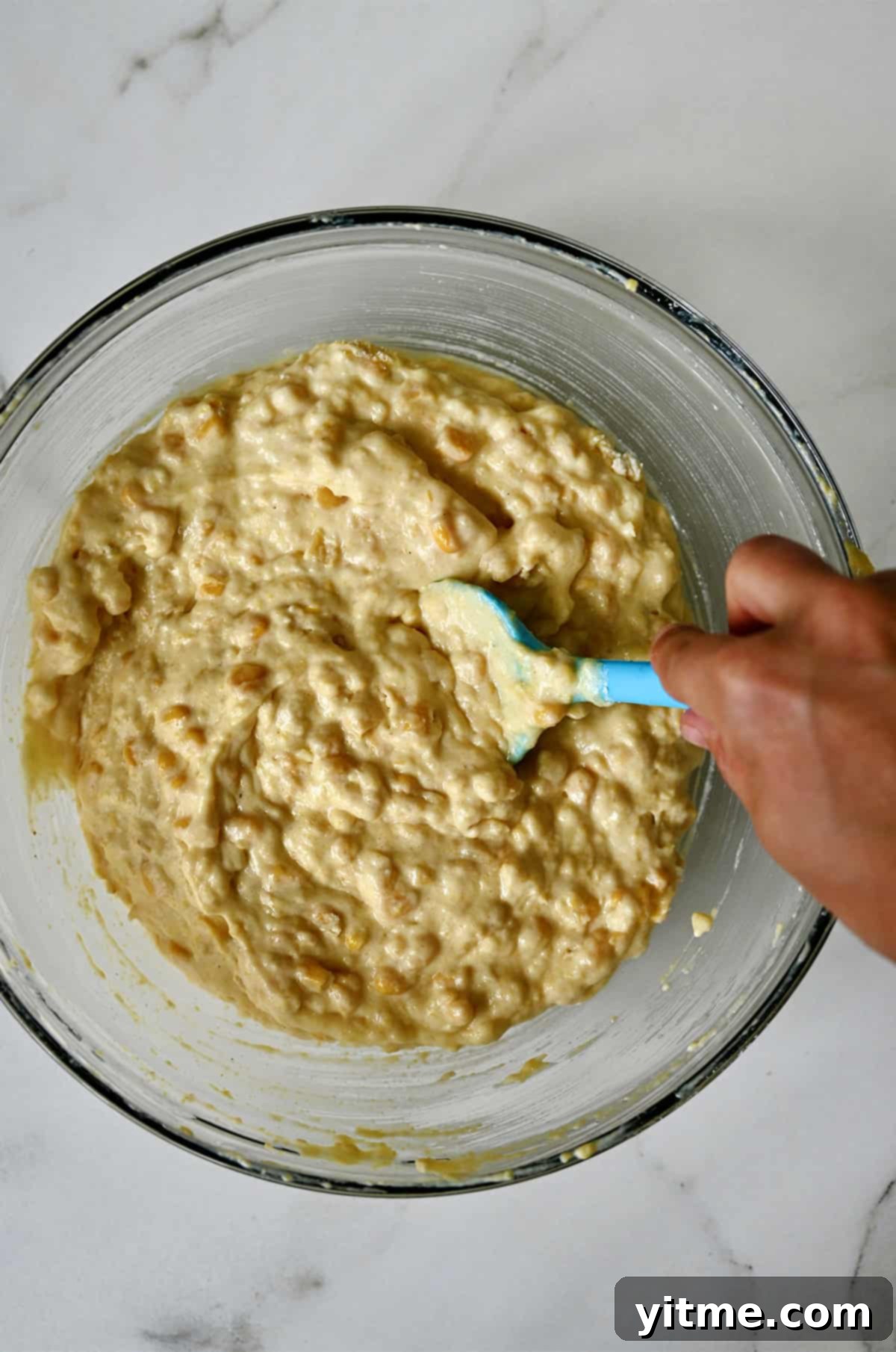 Combining the wet and dry ingredients in a large bowl, mixing just until combined to form a smooth corn casserole batter.