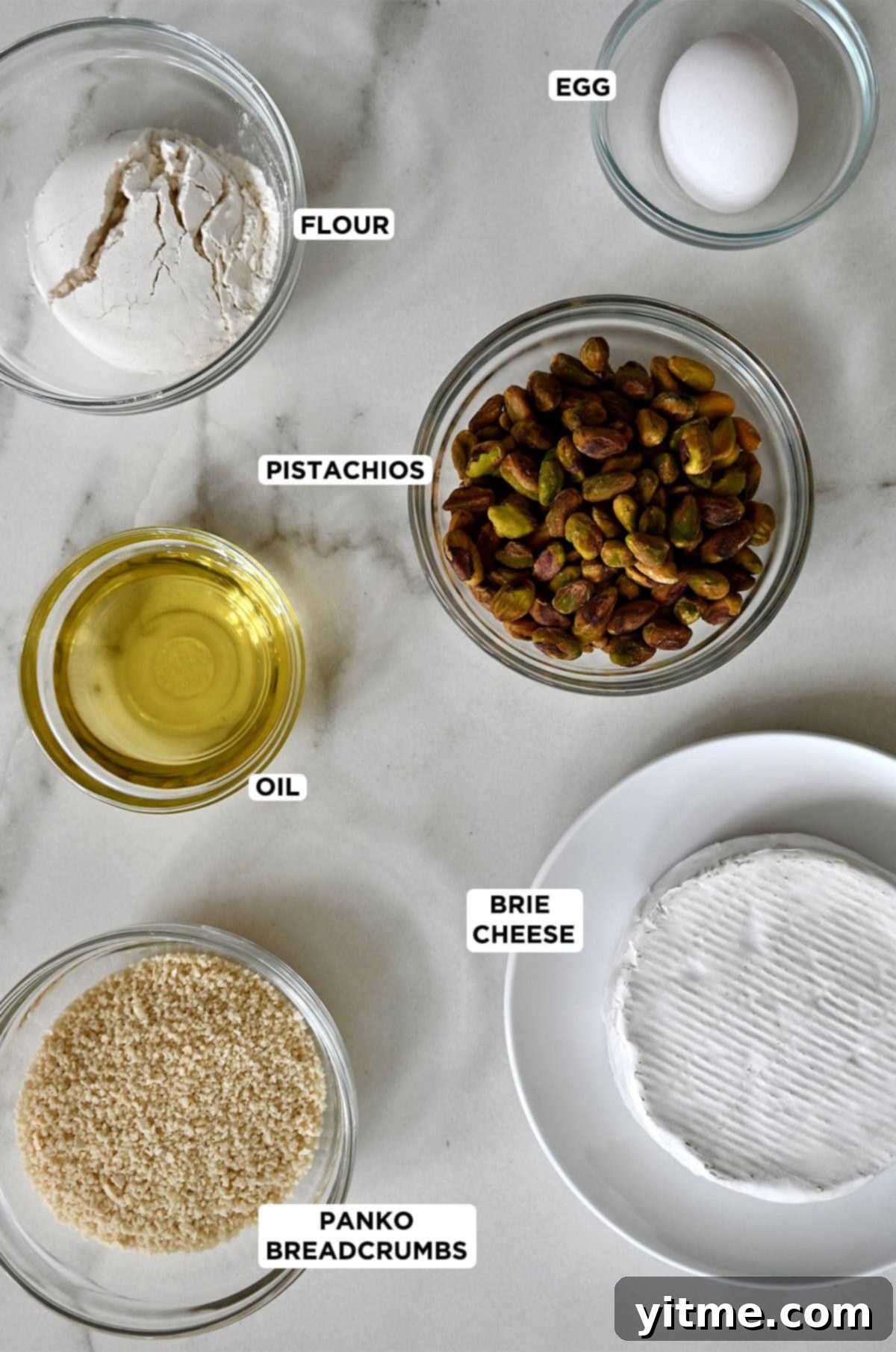 Ingredients for pan-fried brie: brie cheese, pistachios, Panko breadcrumbs, oil, egg, and flour.