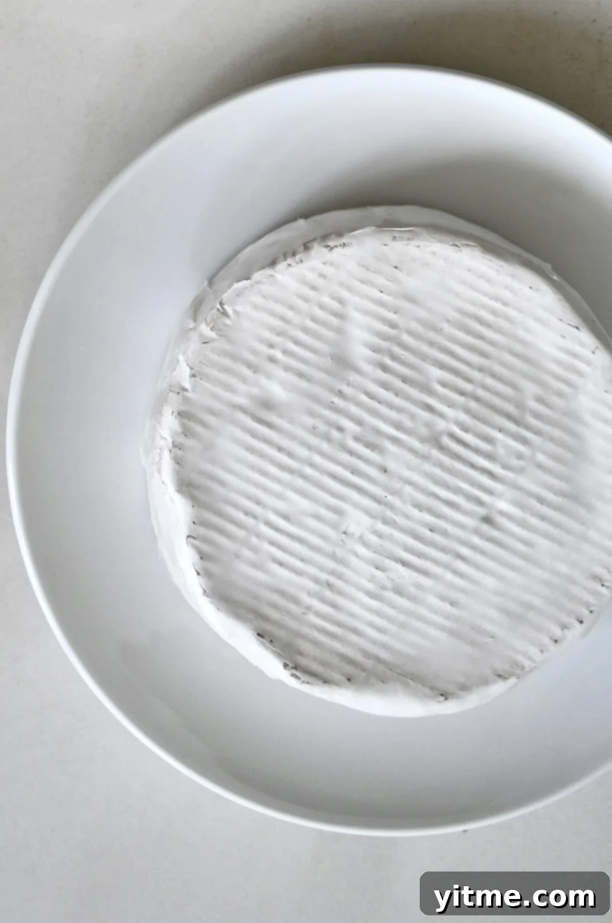 A wheel of Brie cheese on a plate.