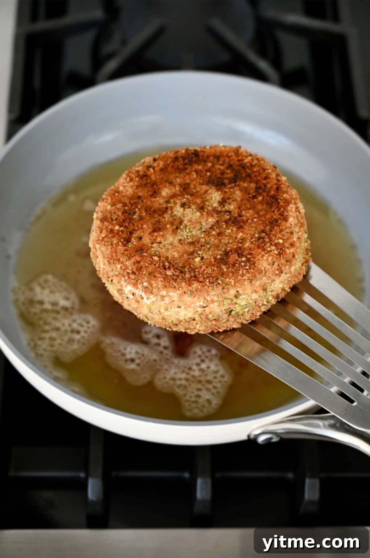 Pan-fried Brie being lifted from hot oil.