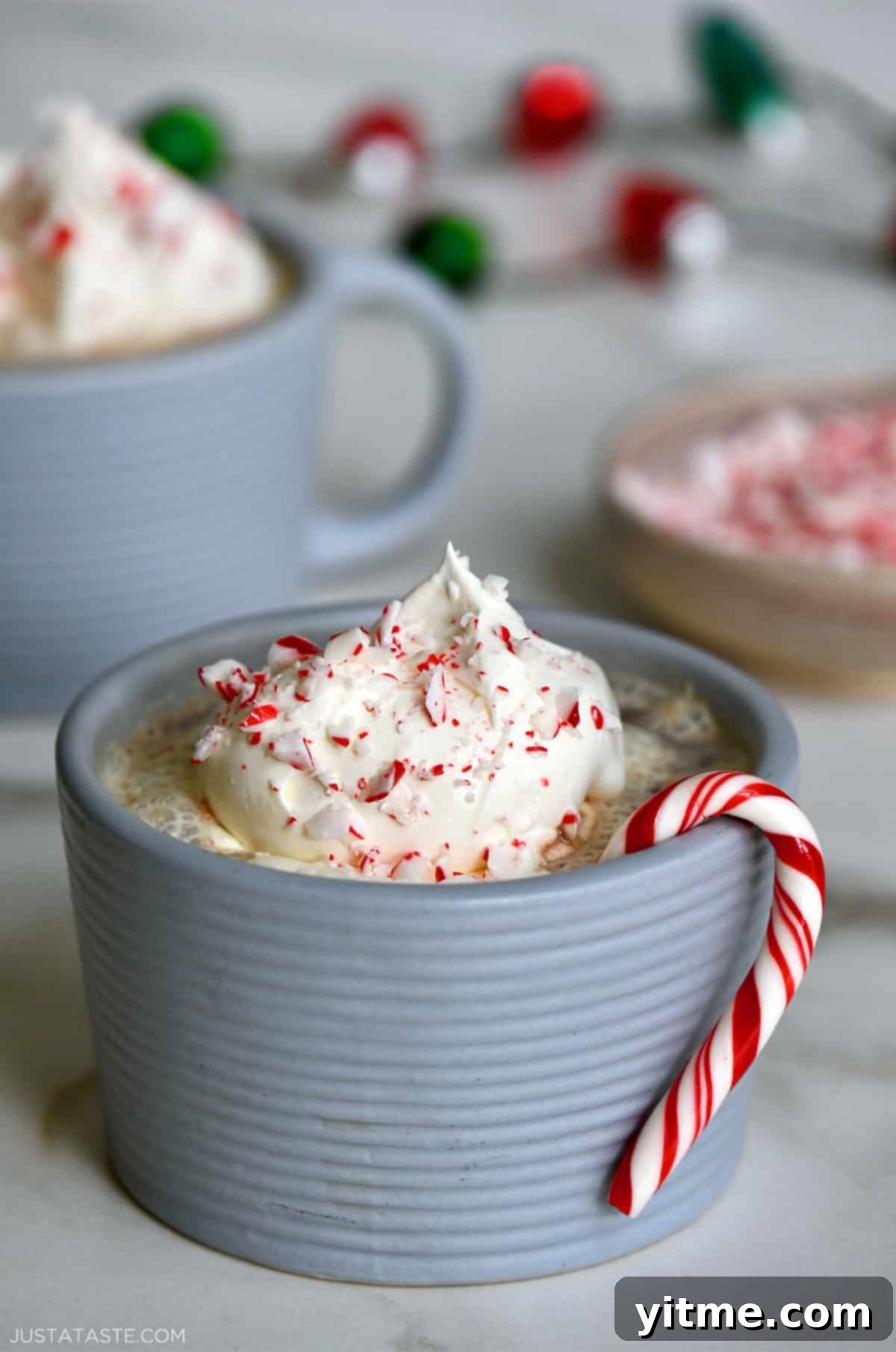 Homemade peppermint mocha with whipped cream, candy canes, and a candy cane hanging off the side of the mug.
