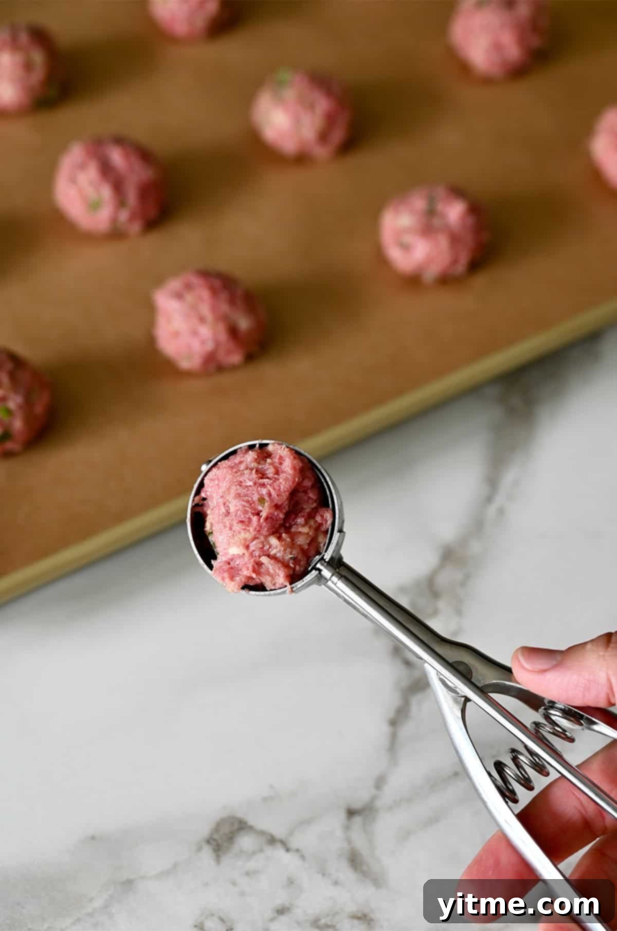 Using a small cookie scoop to make cocktail-sized meatballs.