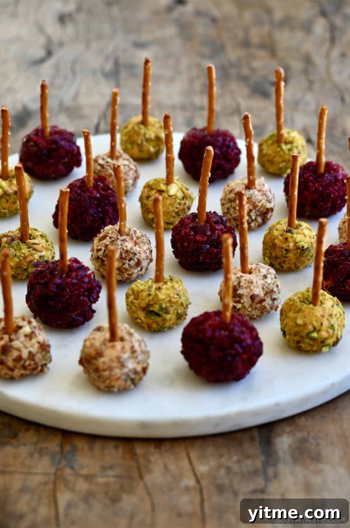Timeless Cheese Ball 11 Mini cheese balls with pretzel sticks on a serving platter.