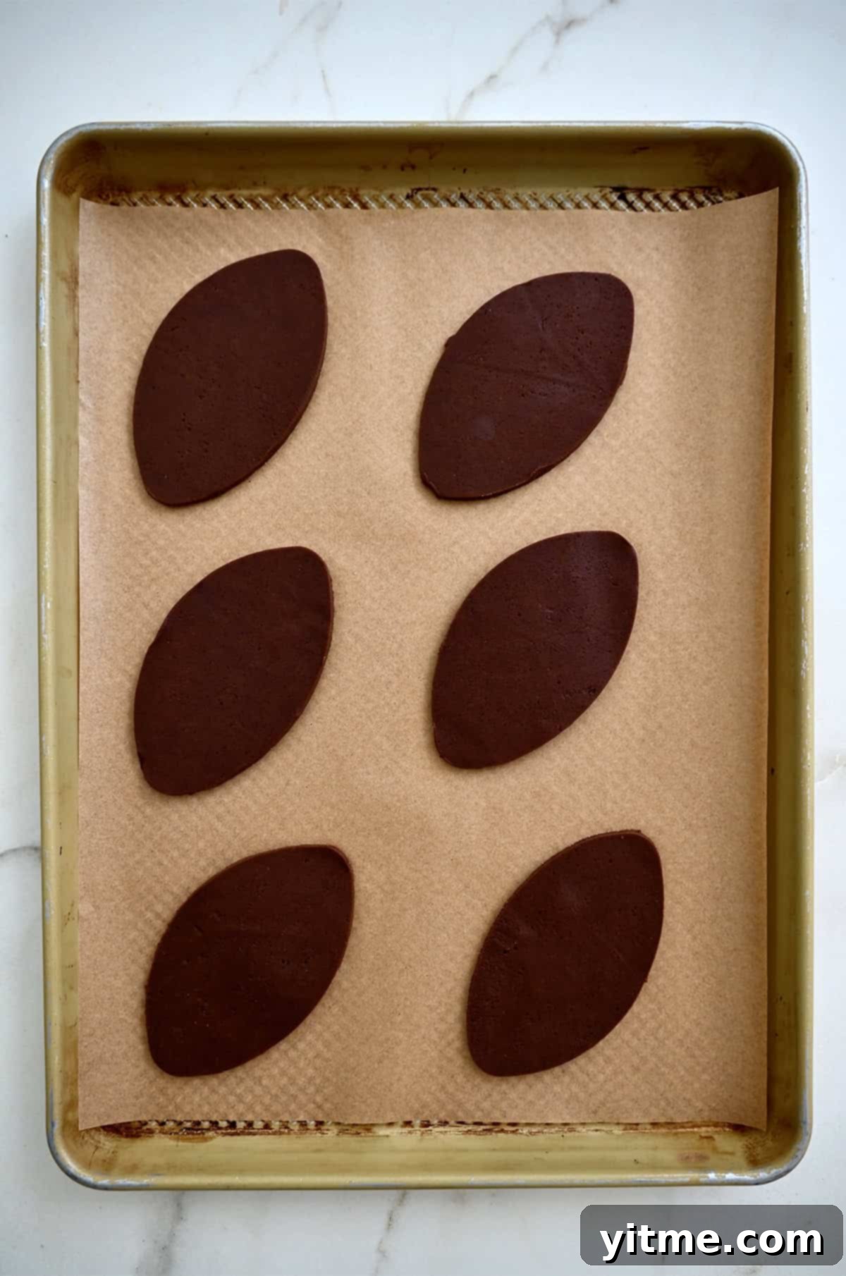 Unbaked football sugar cookies on a baking sheet. The cookies are ready to bake.