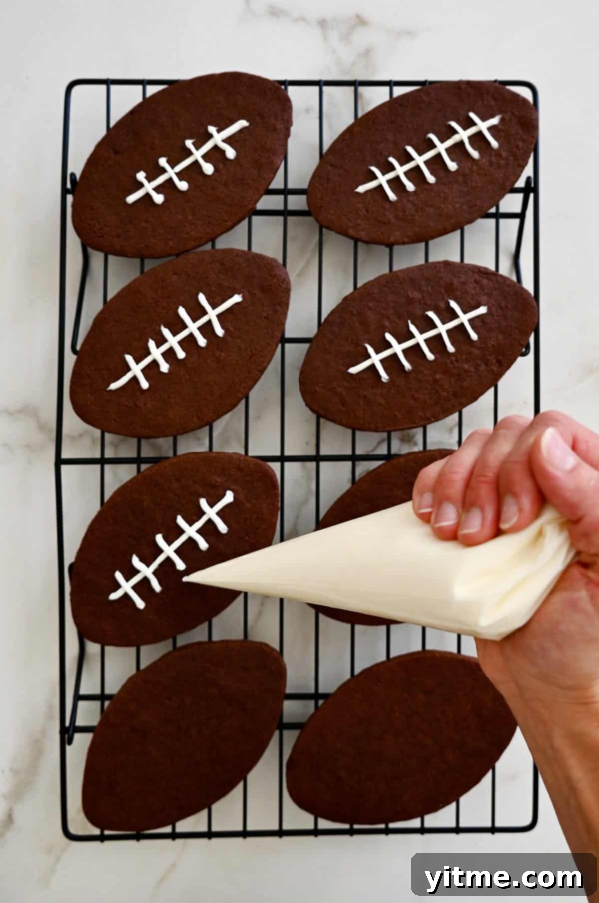 Piping icing onto football cookies to look like laces. A perfect football decoration.