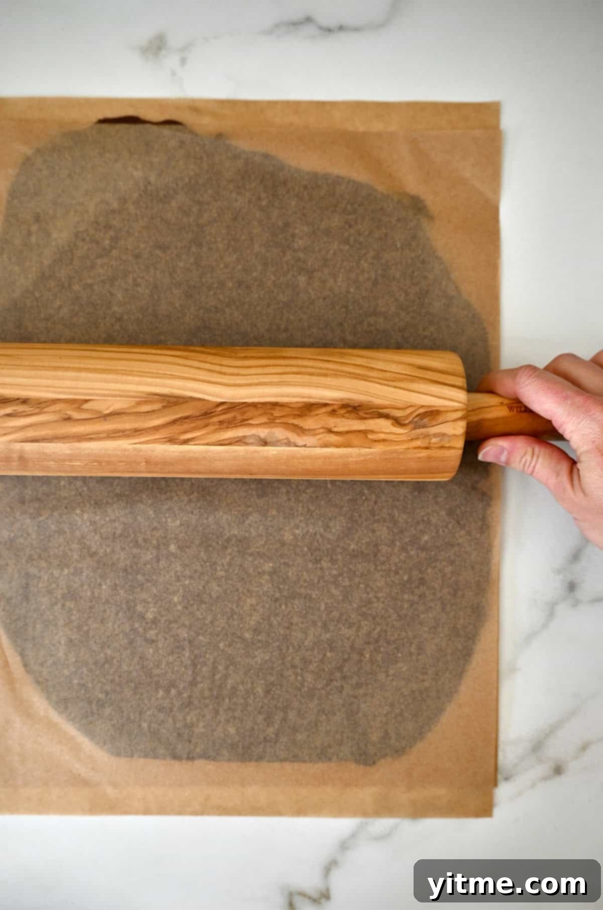 Rolling out chocolate sugar cookie dough between parchment paper. Make football cookies like a pro.