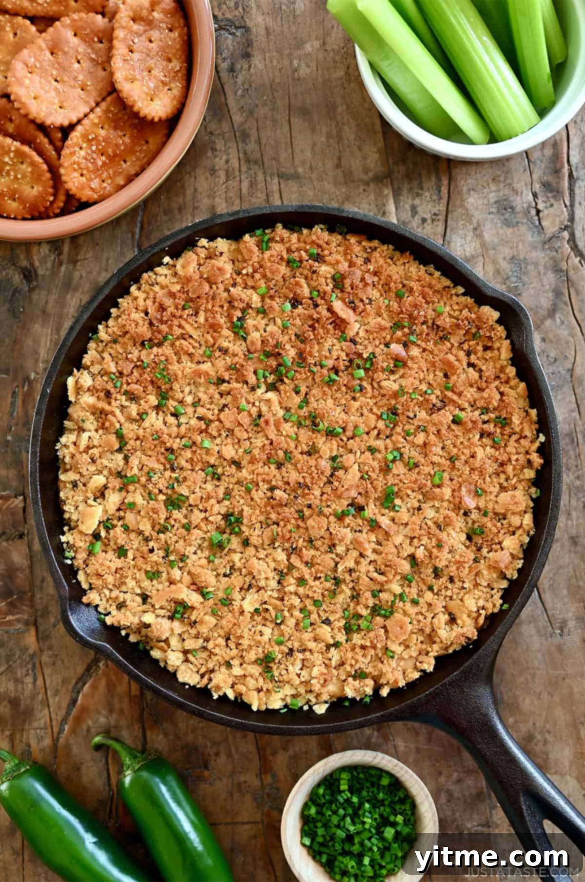 Jalapeño popper dip with a crunchy cracker topping in a cast-iron skillet.