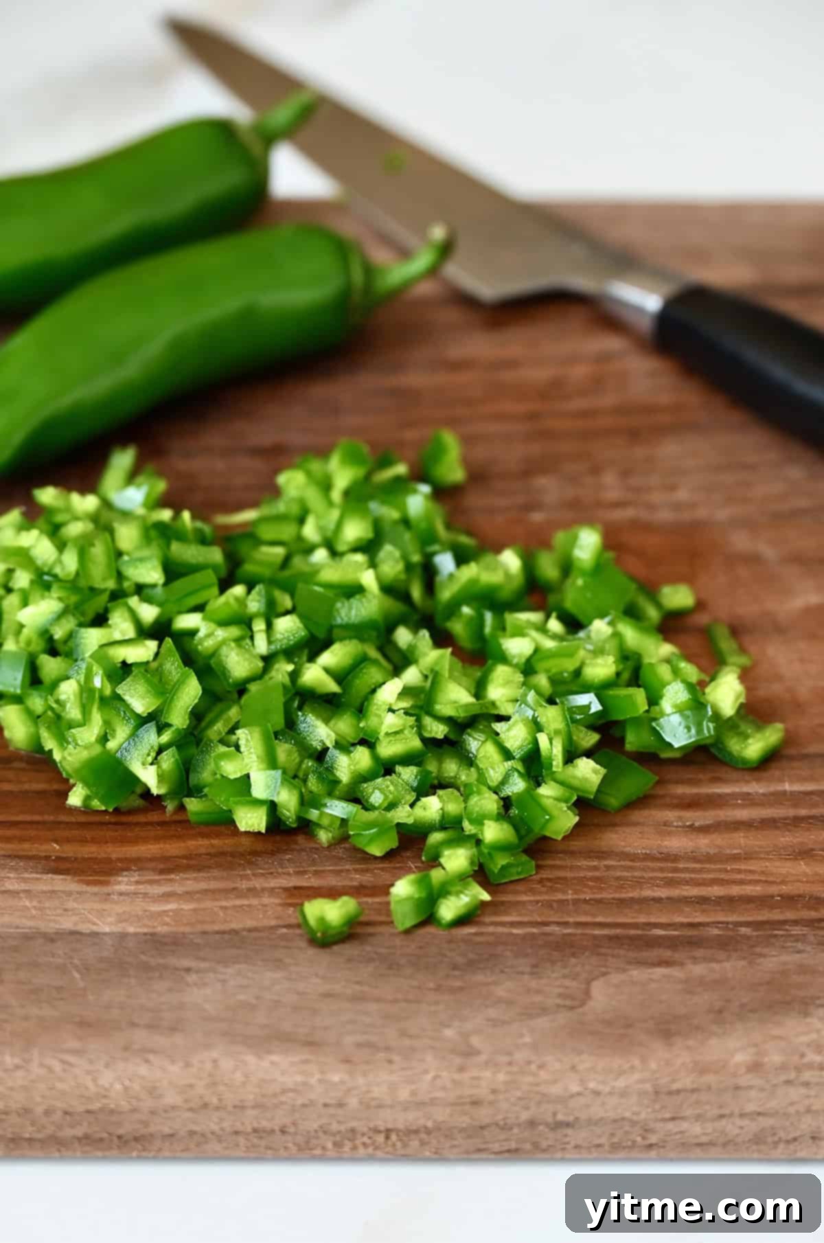 Diced jalapeños on a wood cutting board.