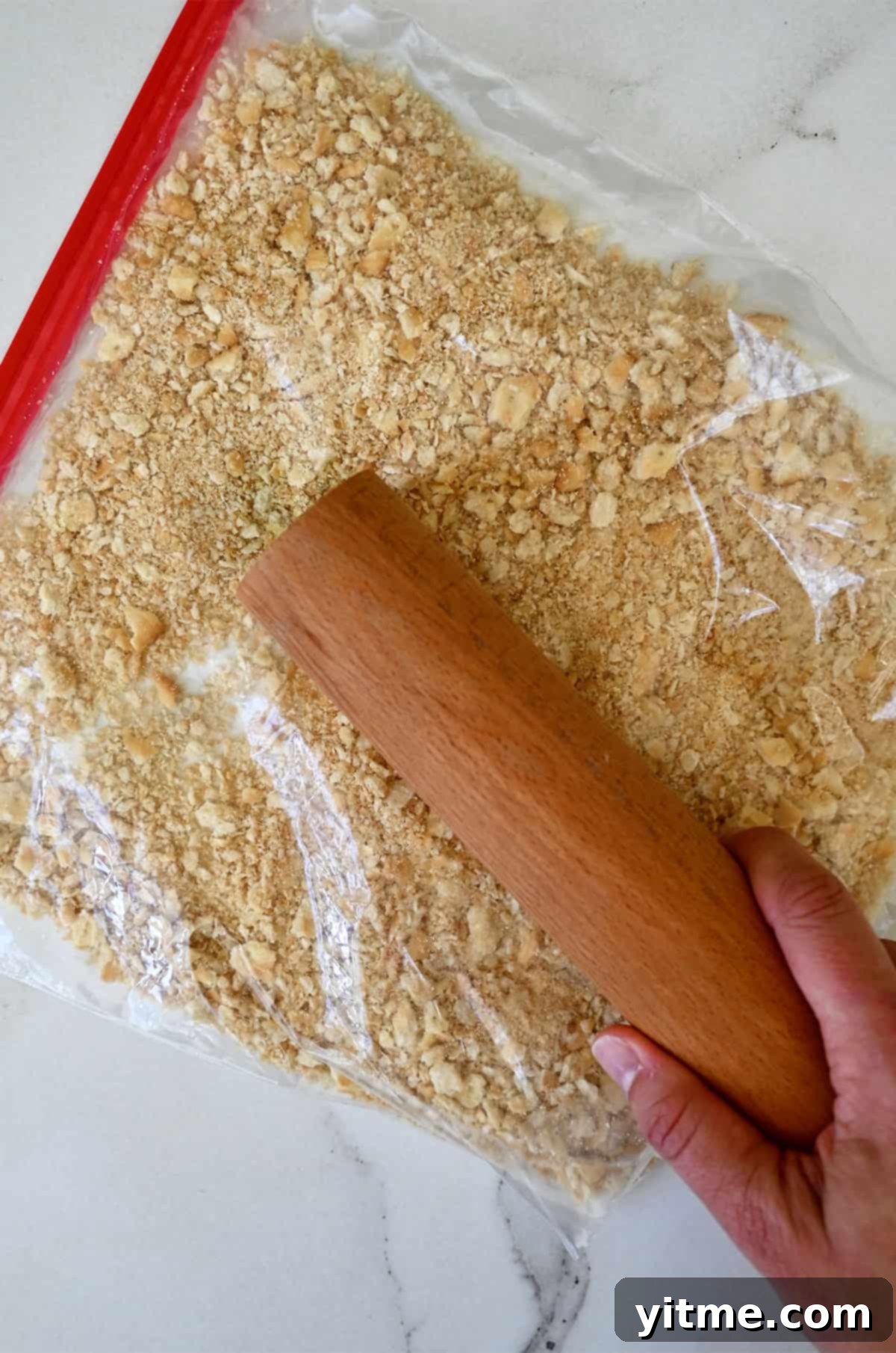 Using a rolling pin to crush crackers in a sealed plastic bag.