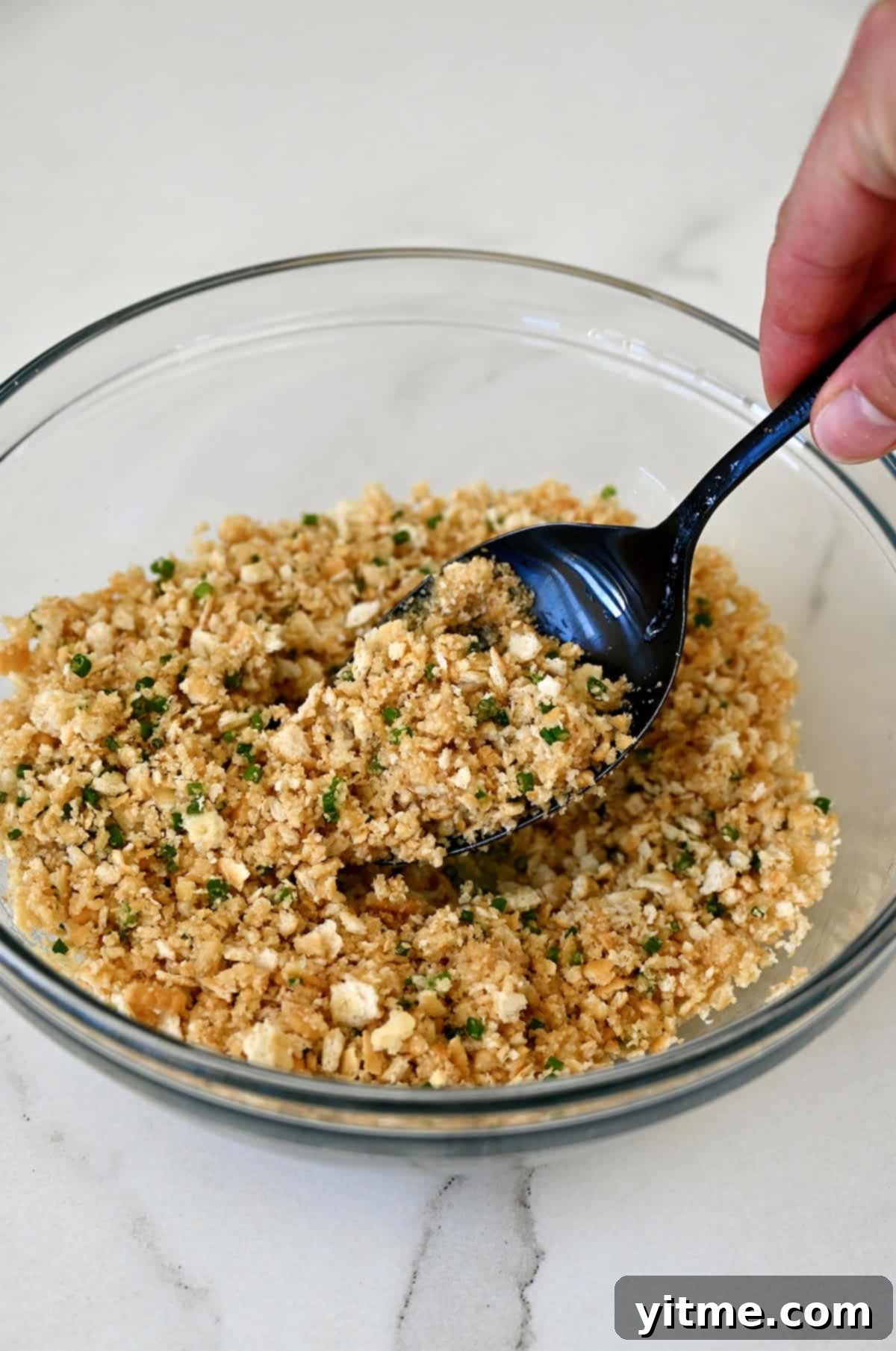 Crumb mixture with chopped fresh chives and melted butter in a small bowl.