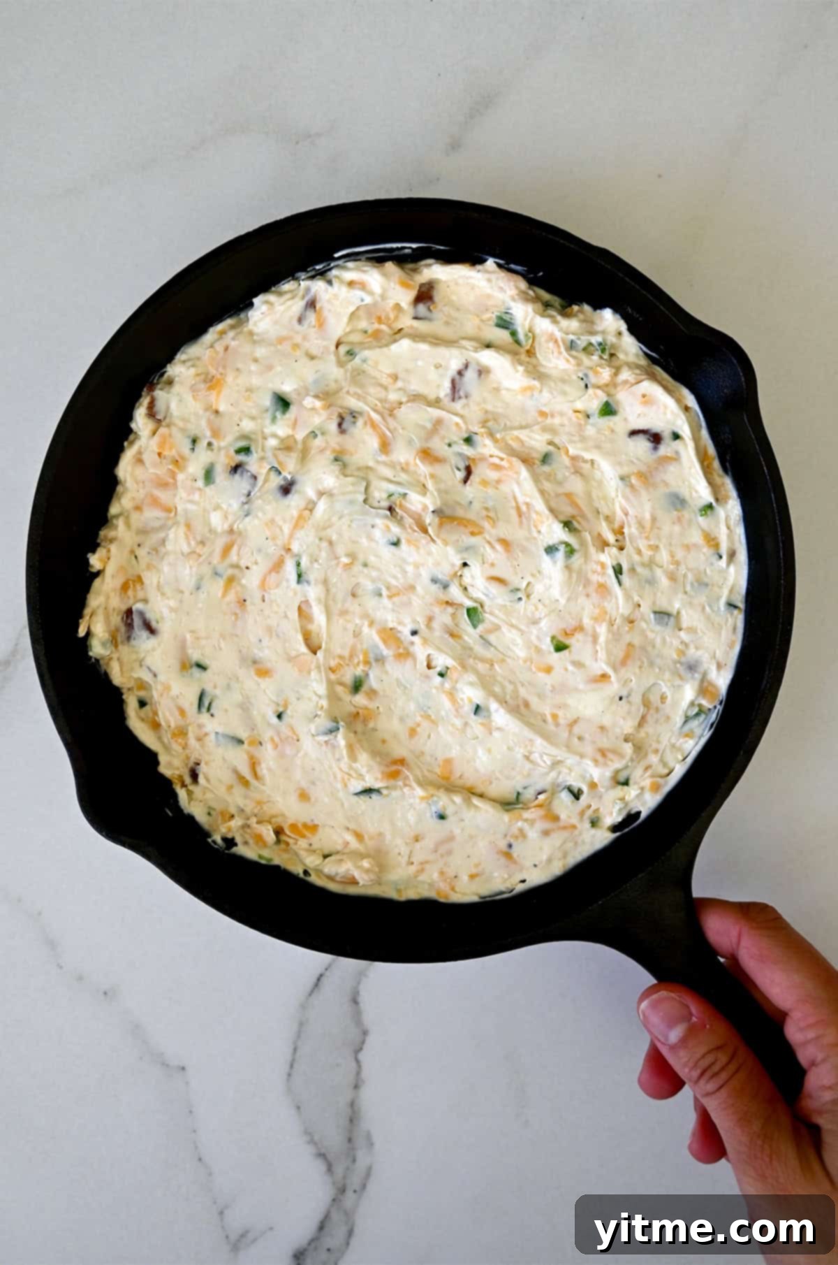 Unbaked cream cheese jalapeño and bacon dip in a cast iron skillet.