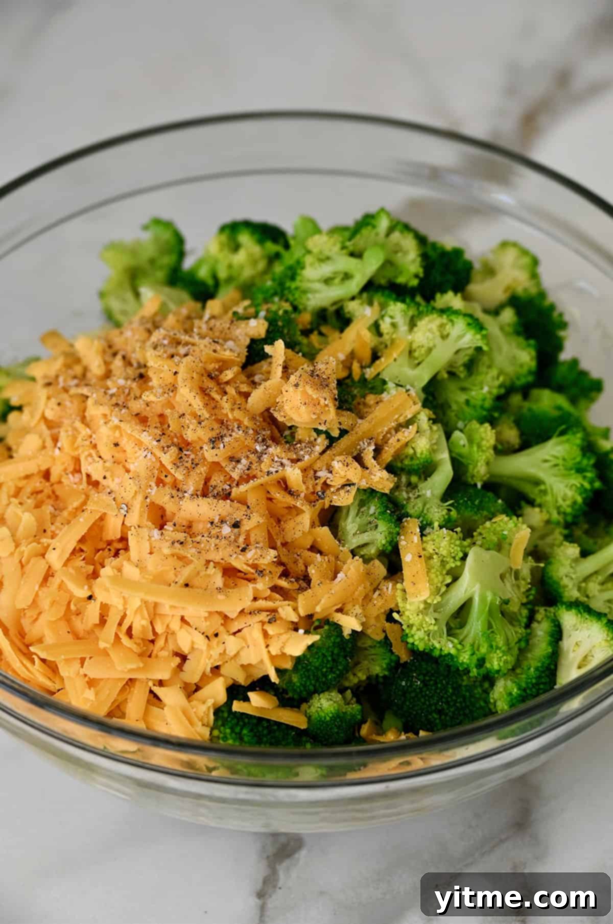 Broccoli florets and cheddar cheese atop cream of mushroom soup in a bowl. Combining broccoli and cheese with the creamy base.