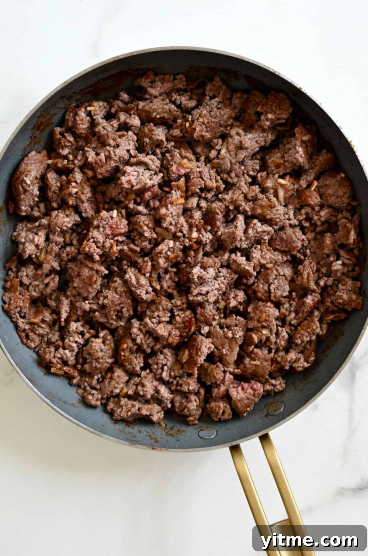 Cooked burger meat in a skillet with the onion soup mix.