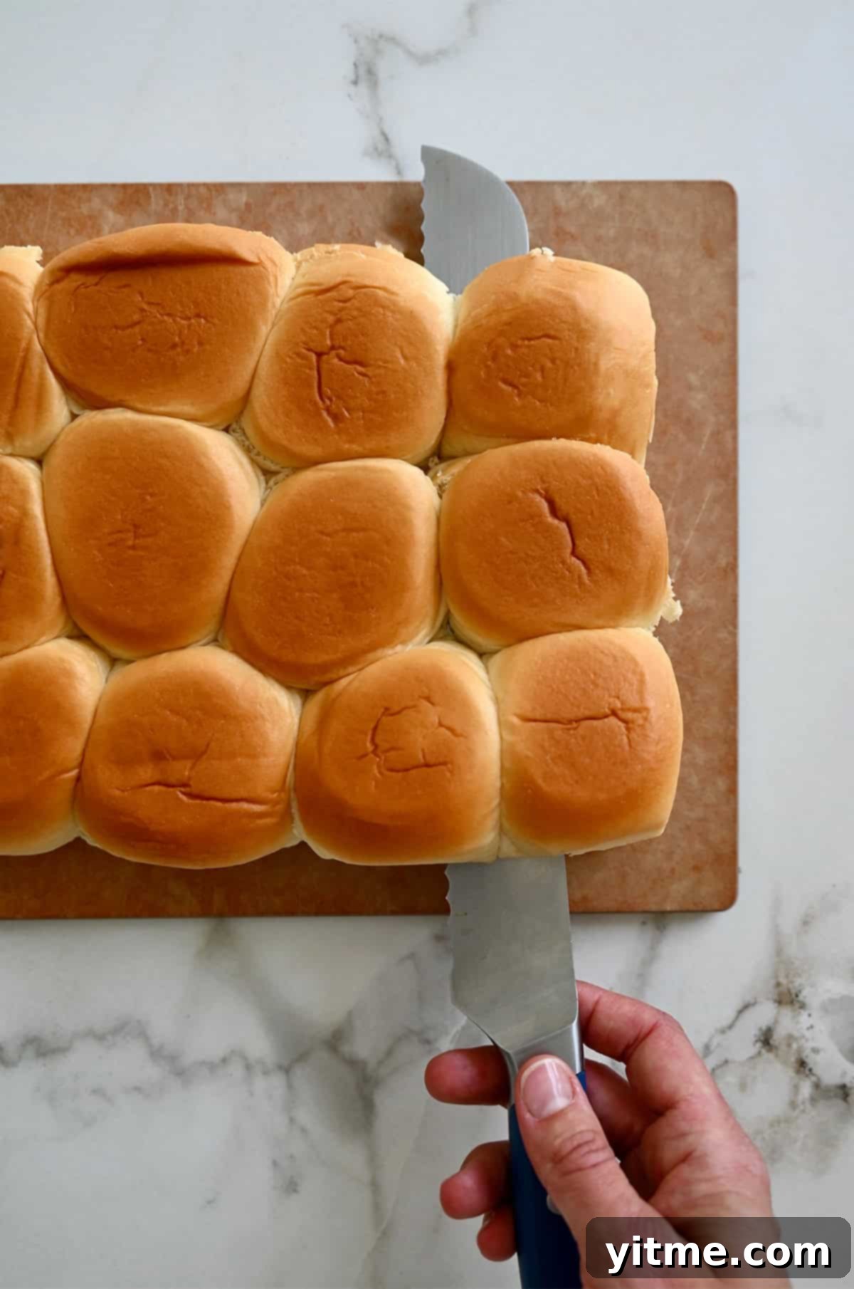 Halving slider rolls with a serrated knife to prepare for layering.