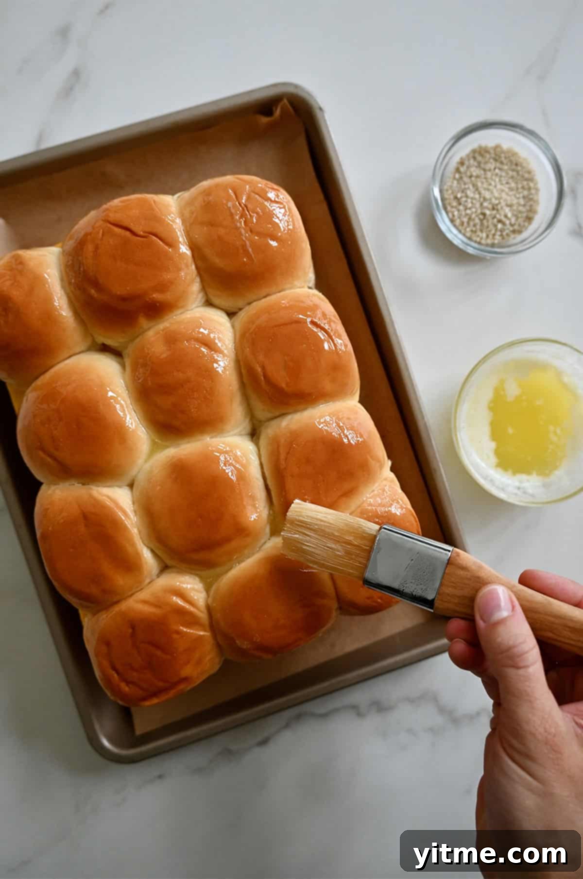 Brushing the tops of the rolls with melted butter before baking.
