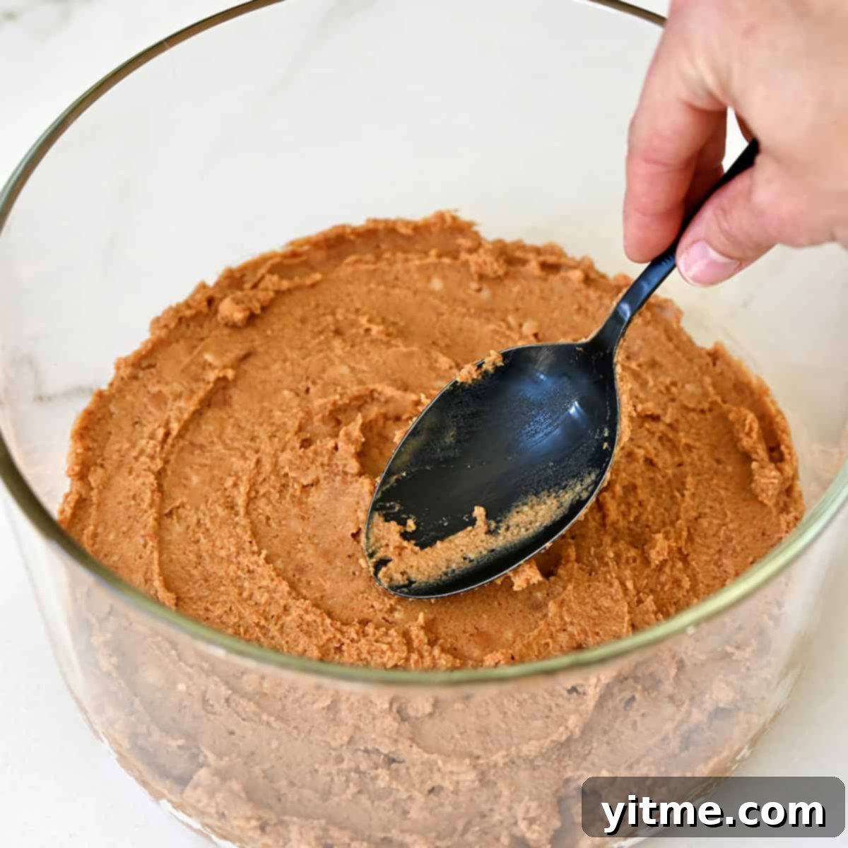 Layering refried beans in a glass dish.