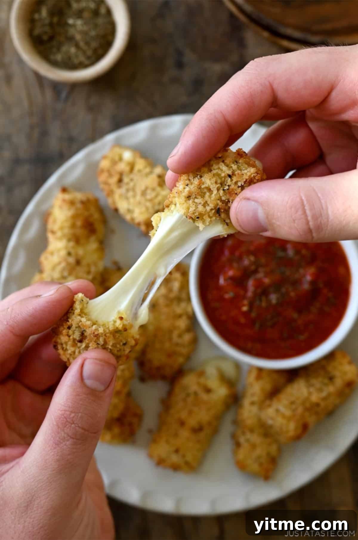 A perfectly pulled, stretchy cheese from a homemade mozzarella stick, demonstrating its gooey texture.