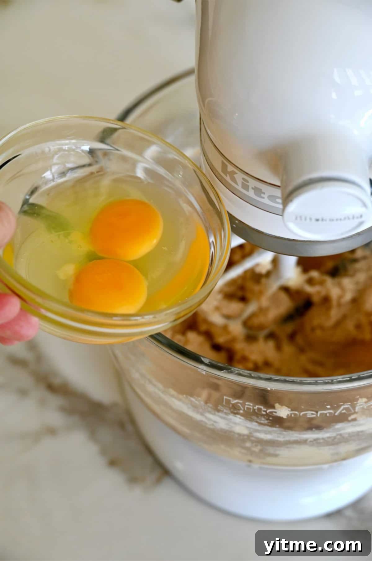 Adding eggs to the creamed sugar and butter mixture.