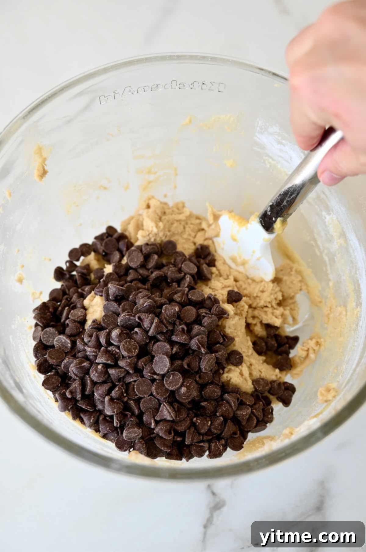 Folding chocolate chips into cookie dough.