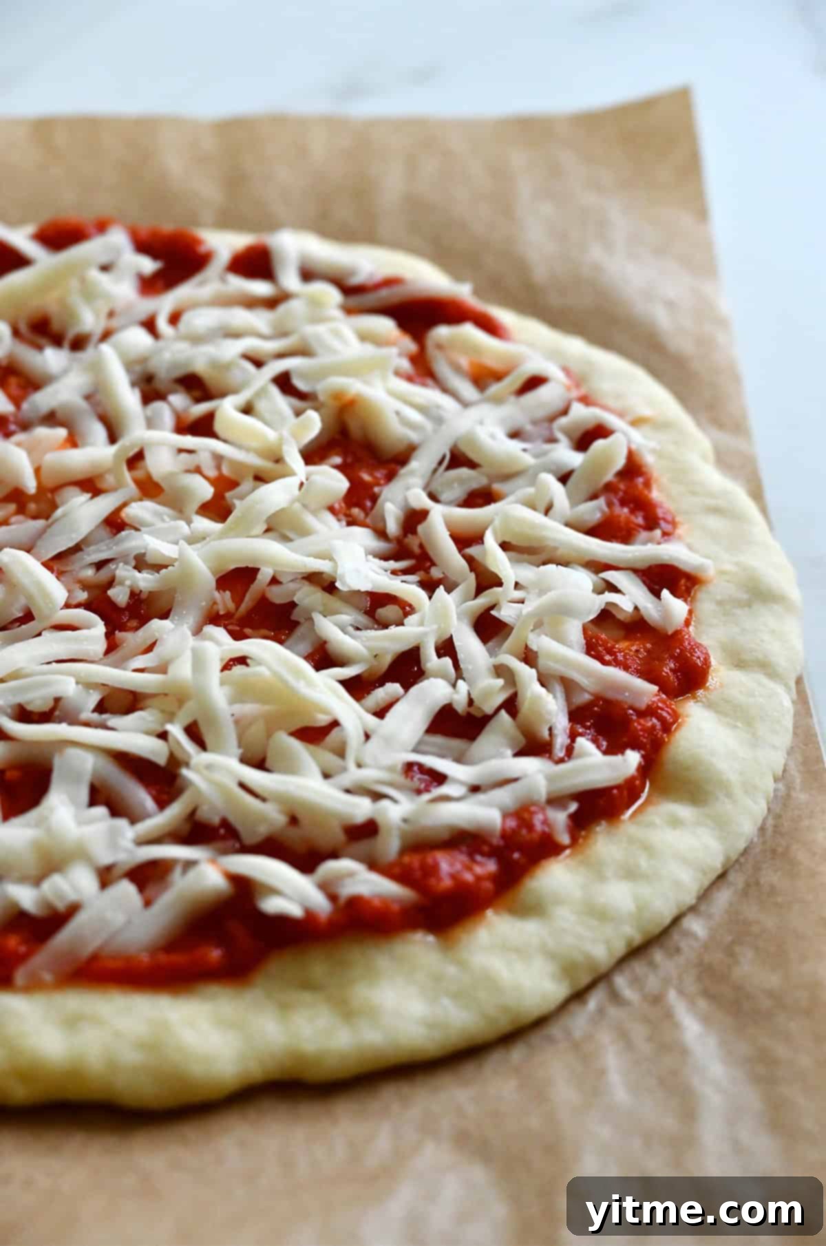 Pizza dough topped with marinara sauce and shredded mozzarella cheese.