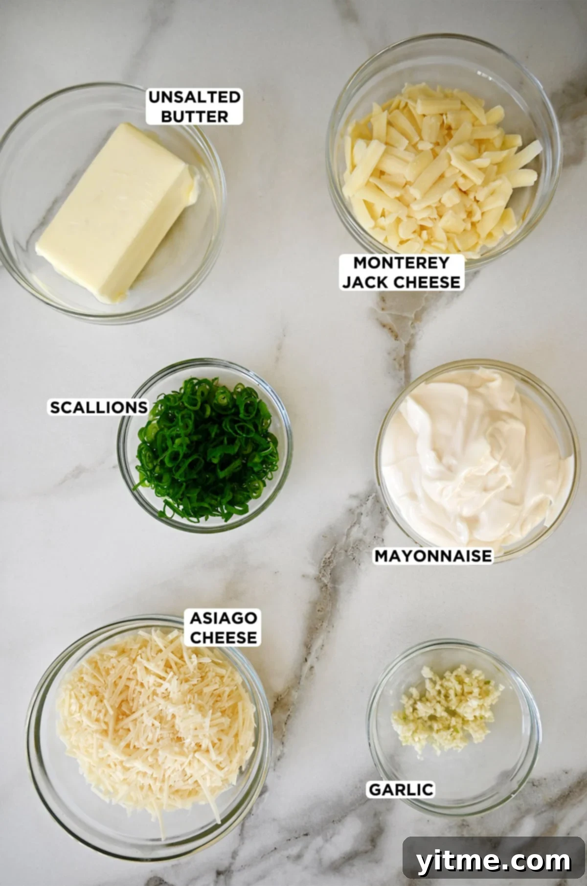 The Unexpected Twist: Cheesy Garlic Bread 3 Glass bowls containing cheesy garlic bread ingredients: butter, Monterey Jack cheese, mayonnaise, scallions, Asiago cheese, and minced garlic.