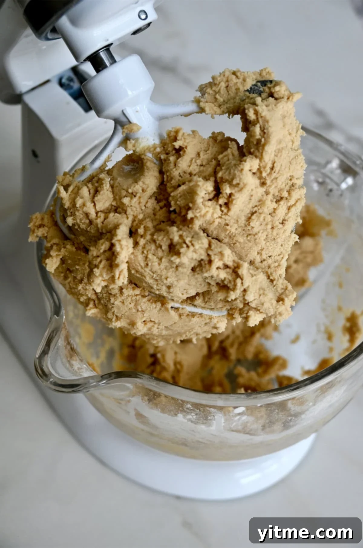 Vanilla Bean Dream Cookies 7 Chipless cookie dough clinging to the paddle attachment of a stand mixer. A smooth and luscious dough ready to be transformed.