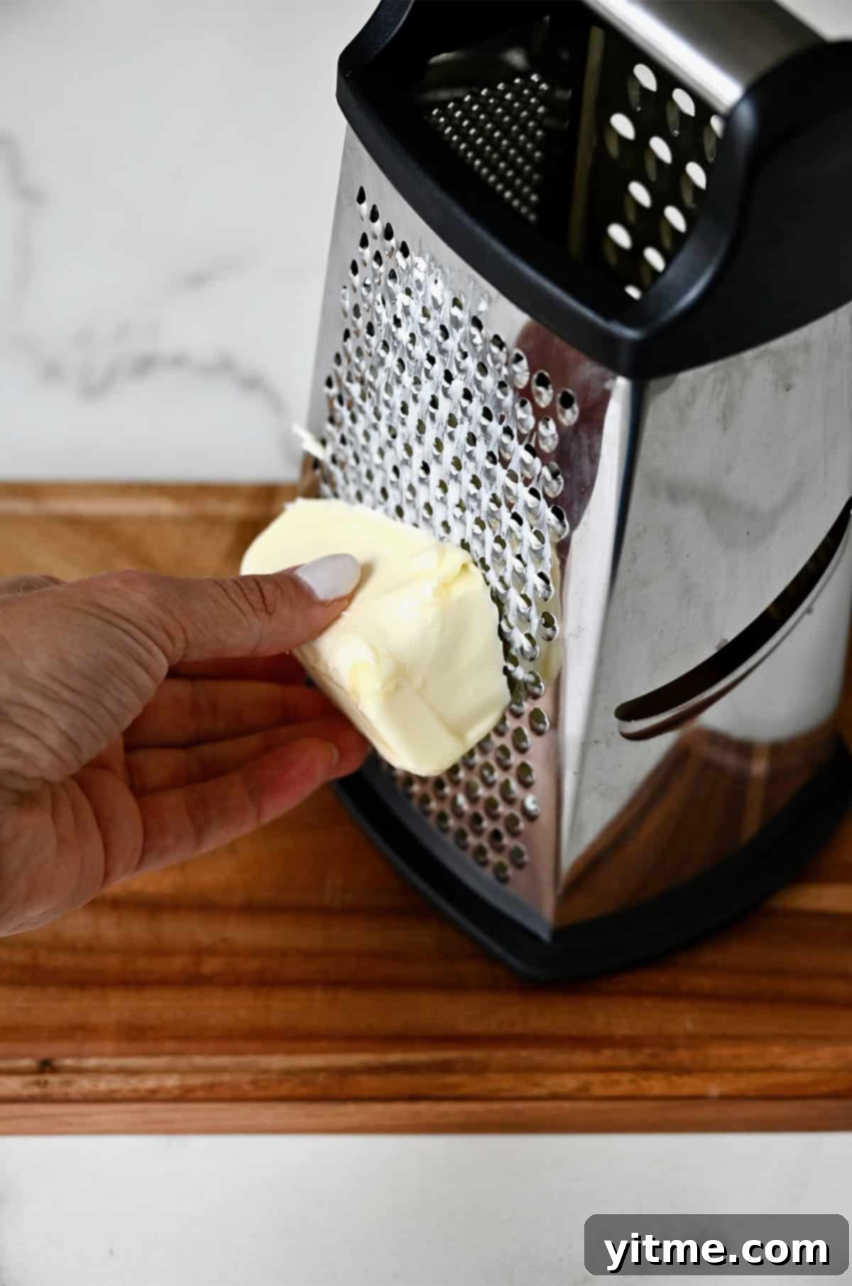 Grating cold butter using a box grater.