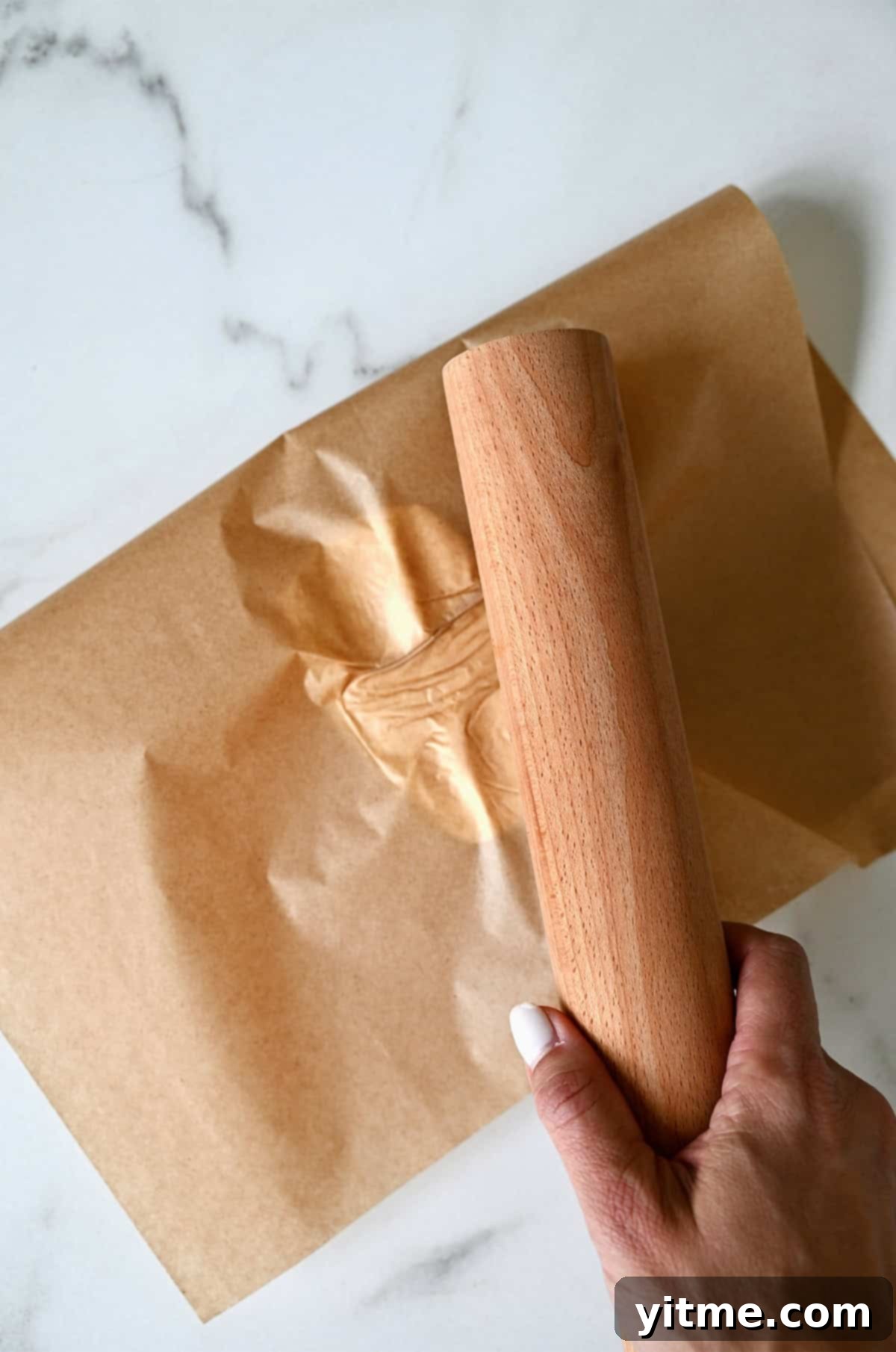 Pounding butter between parchment paper with a rolling pin.
