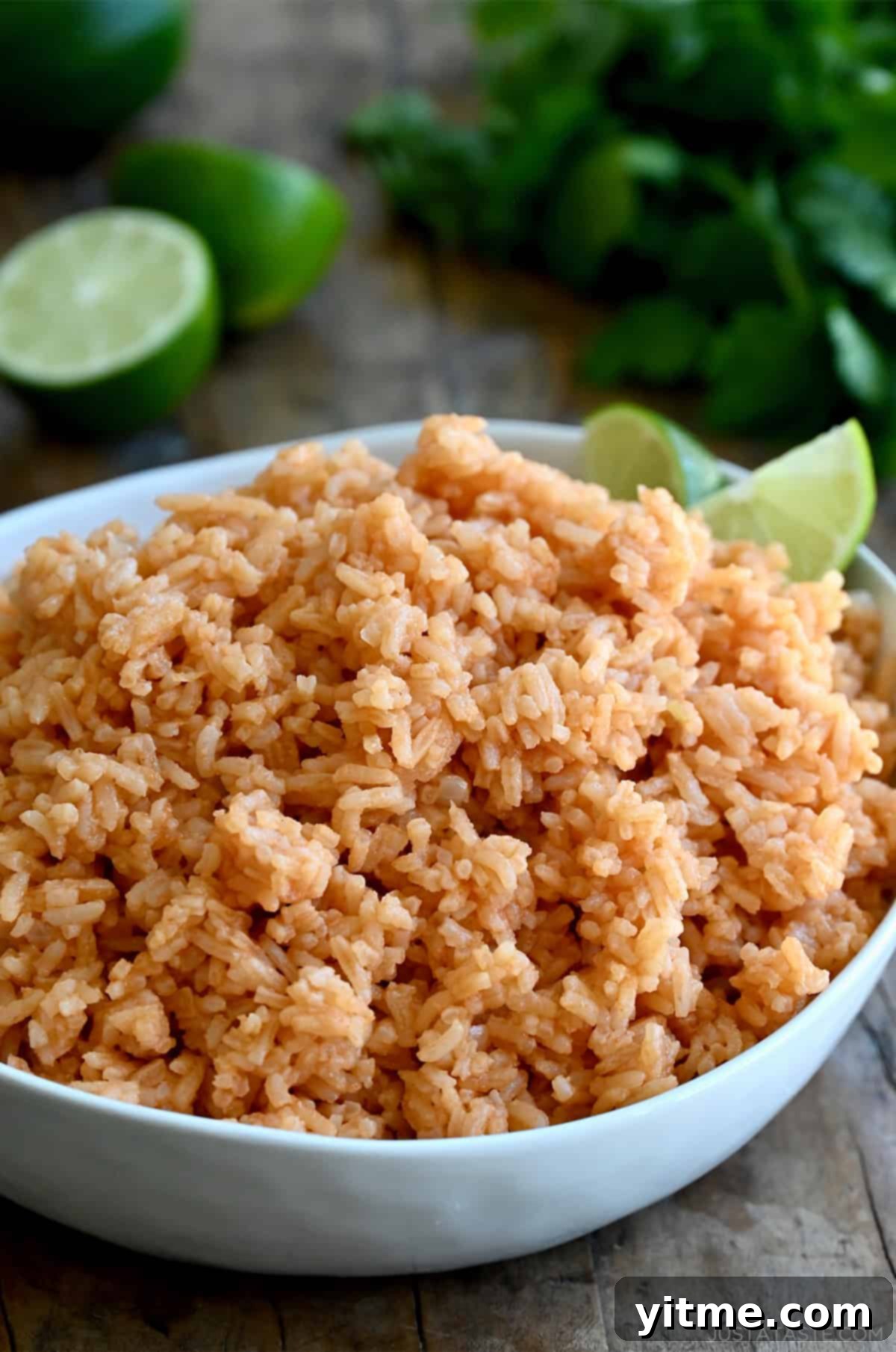 Vibrant Mexican Rice: A Flavorful Fiesta 10 Mexican rice in a serving bowl with two lime wedges.
