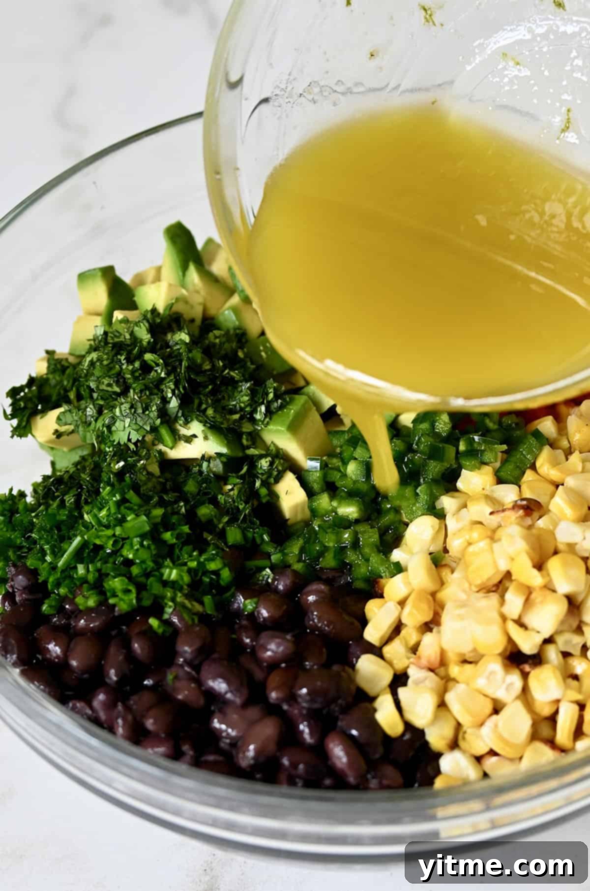 Pouring lime vinaigrette over black bean and corn mixture.
