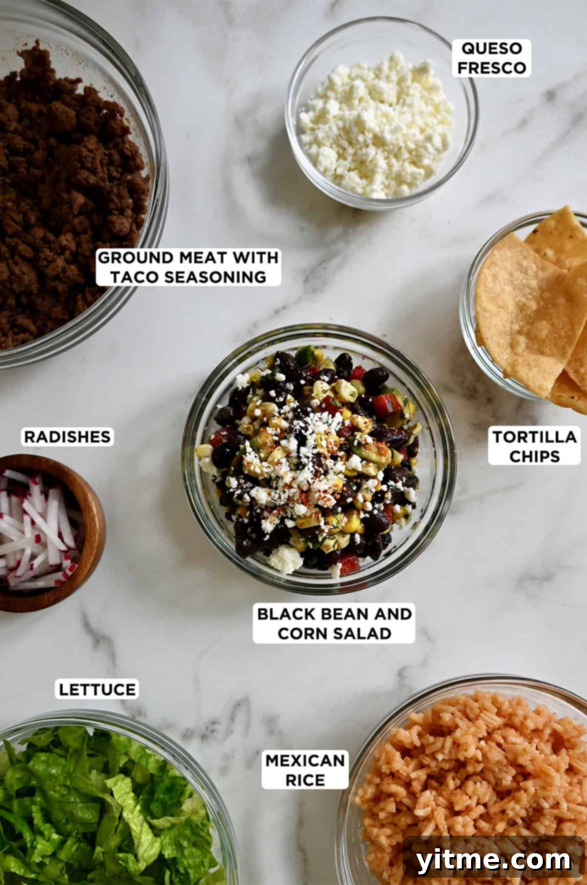 Bowls filled with seasoned ground beef, crumbled queso fresco, crispy tortilla chips, vibrant black bean and corn salad, fluffy Mexican rice, shredded lettuce, and thinly sliced radishes, showcasing the diverse components ready for building a personalized taco bowl.