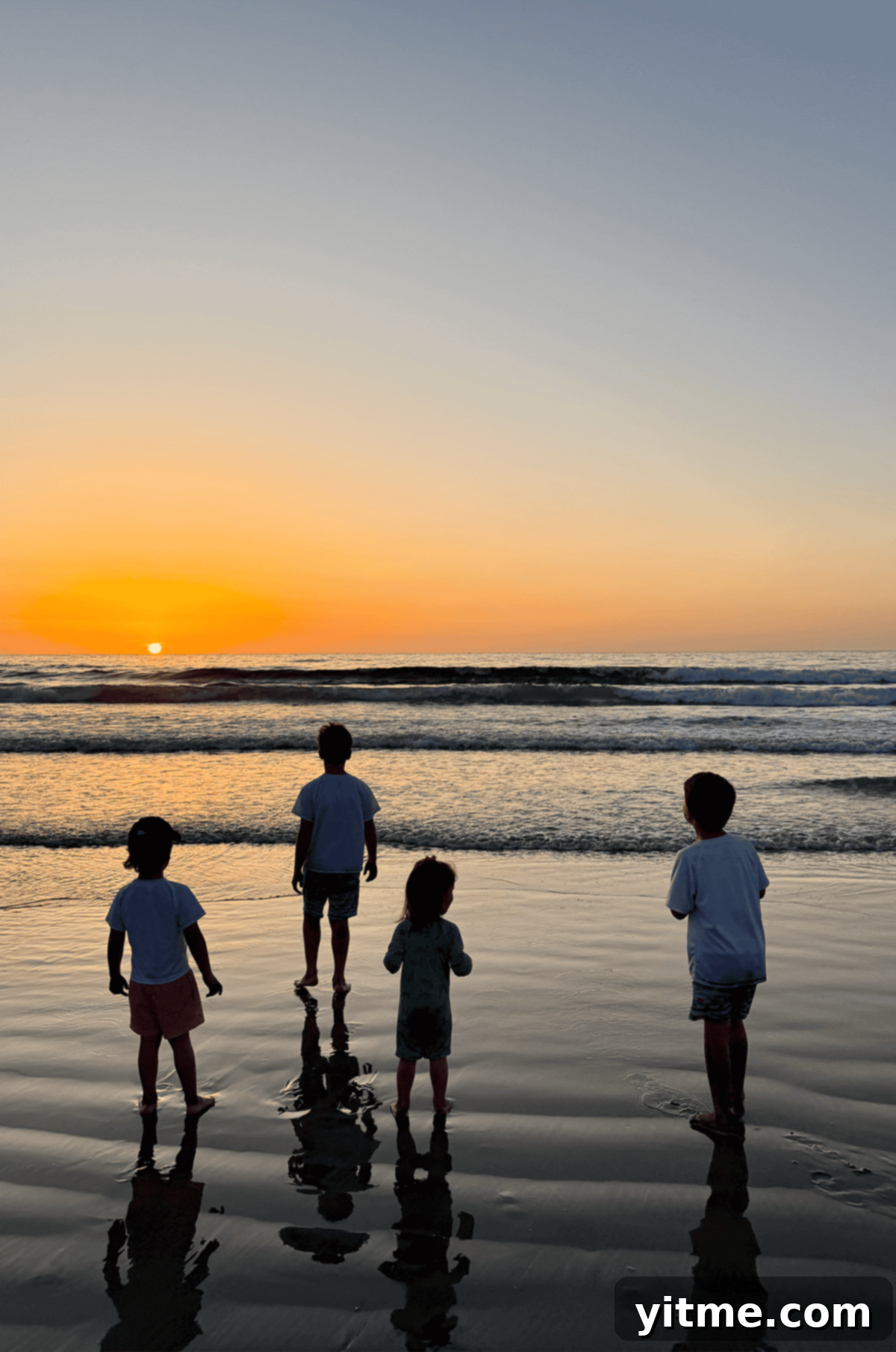 Four kids standing on a San Diego beach watching the sunset, signaling the start of summer.