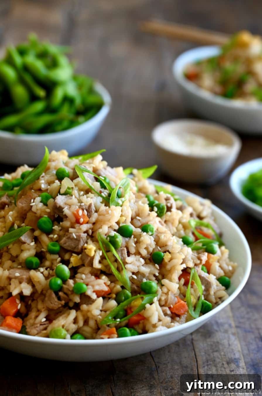 A white bowl containing Pork Fried Rice with peas and carrots.