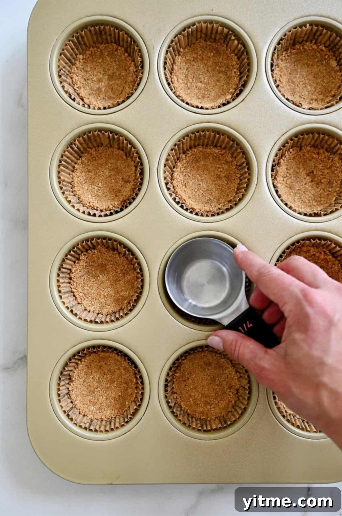 Pressing graham cracker crust into muffin tin