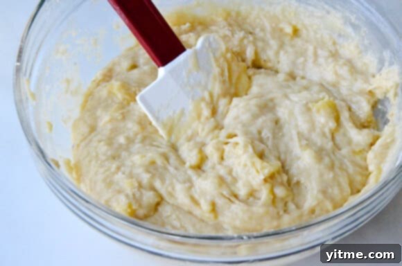 Banana bread batter in a large glass mixing bowl.