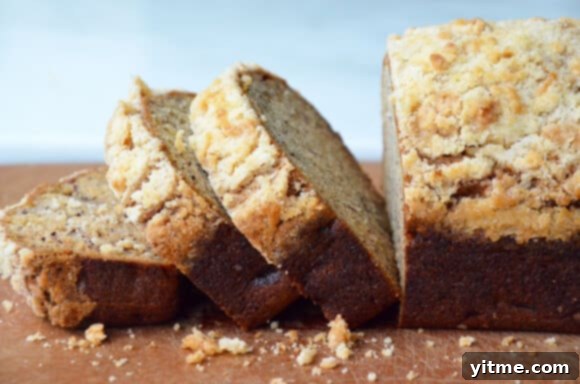 A loaf of banana bread sliced on a wooden cutting board.