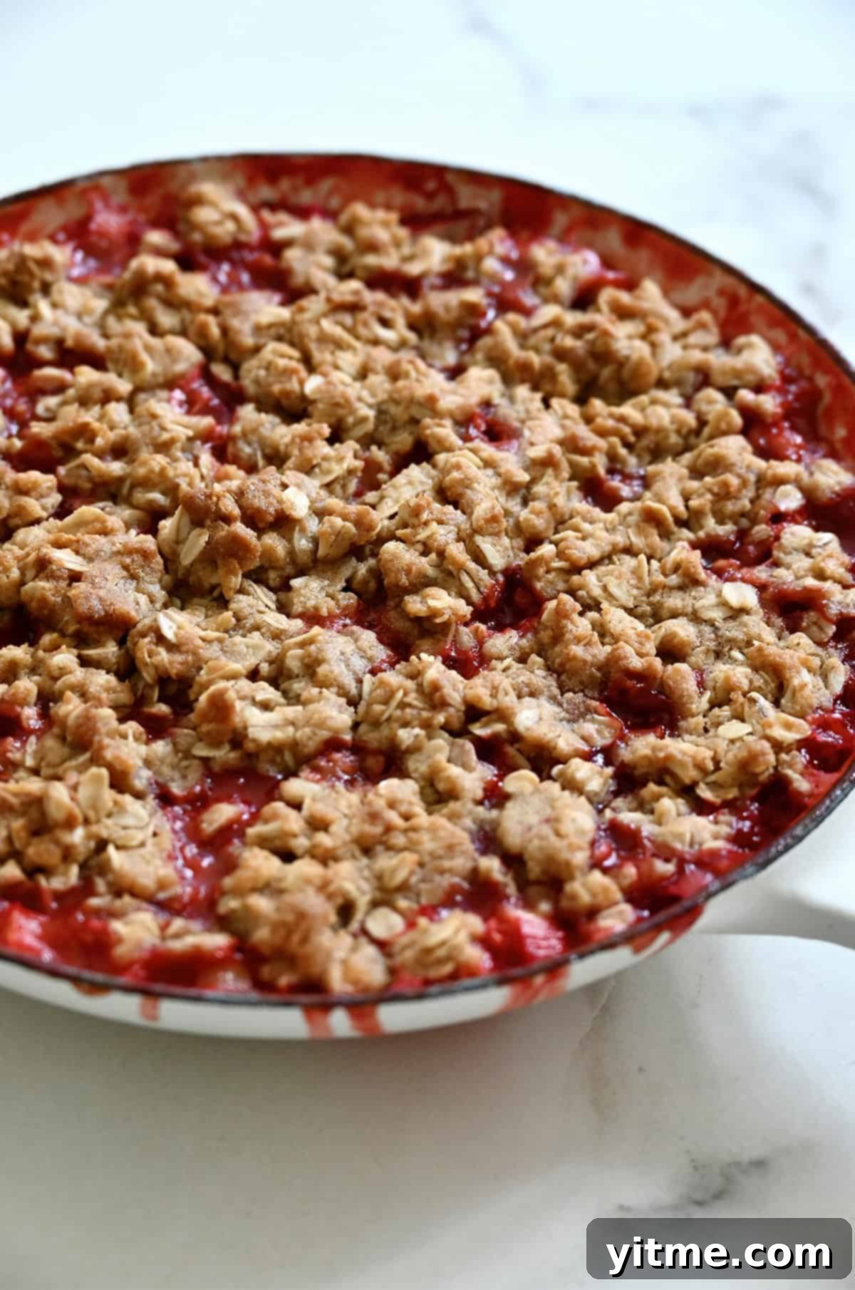 Golden brown and bubbling rhubarb strawberry crisp in a skillet.
