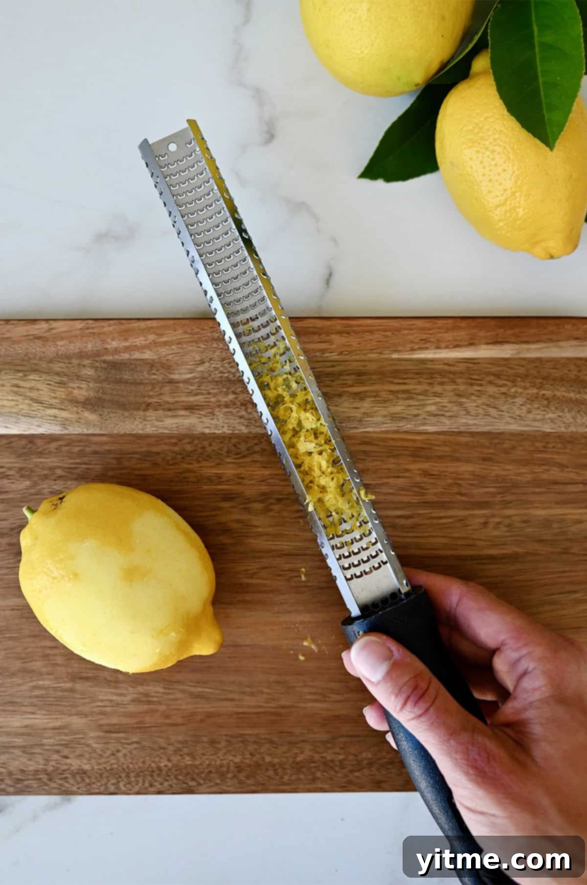 Zesting Lemons: A Citrus Twist Guide 3 Demonstration of zesting a lemon with a microplane over a cutting board.