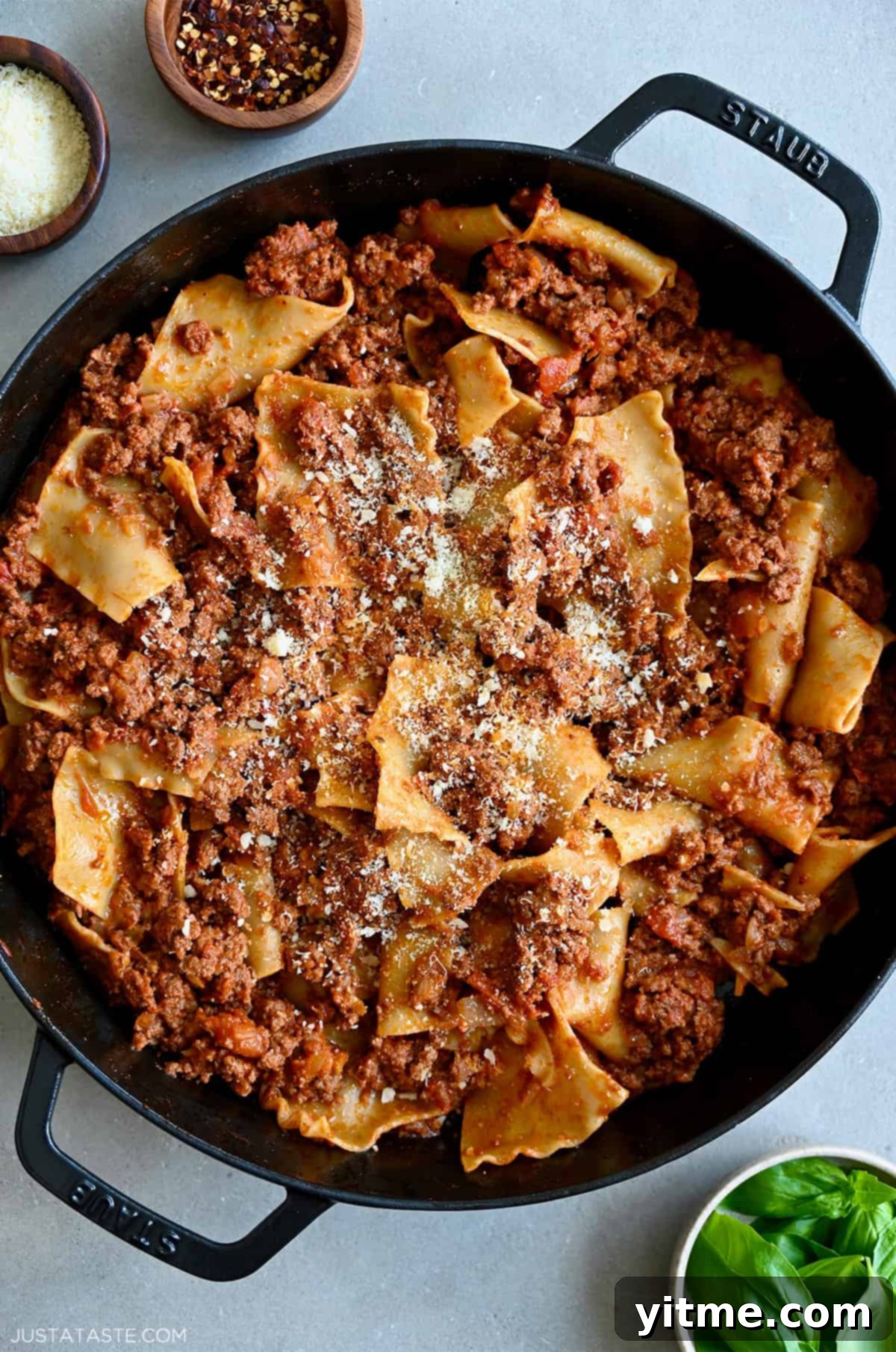 A bubbling cast iron skillet filled with hearty ground beef lasagna, garnished with freshly grated Parmesan cheese. This skillet lasagna is a quick and easy alternative to traditional lasagna, perfect for weeknight dinners.