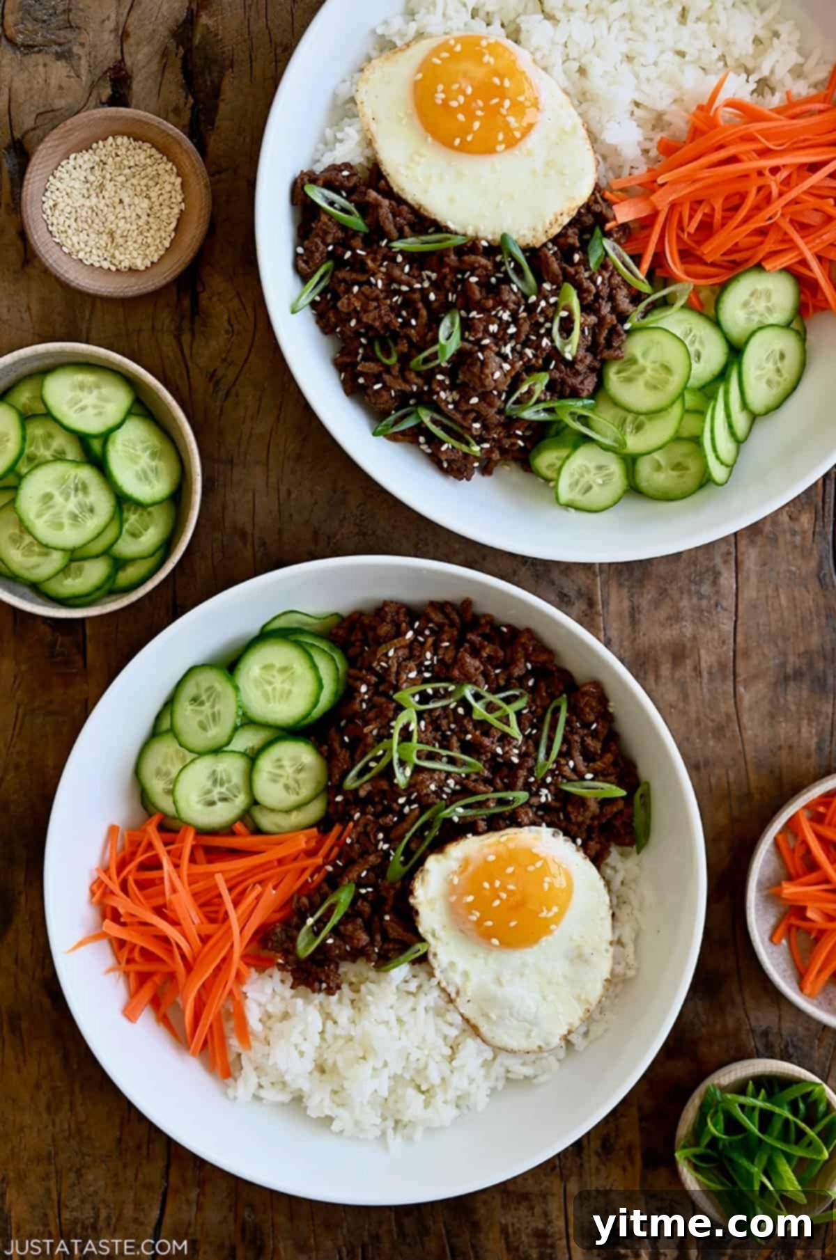 Two bowls filled with Korean beef, steamed white rice, shredded carrots, sliced cucumber, and a fried egg. These Korean beef bowls are bursting with bold and savory flavors, making them a quick and easy weeknight meal.